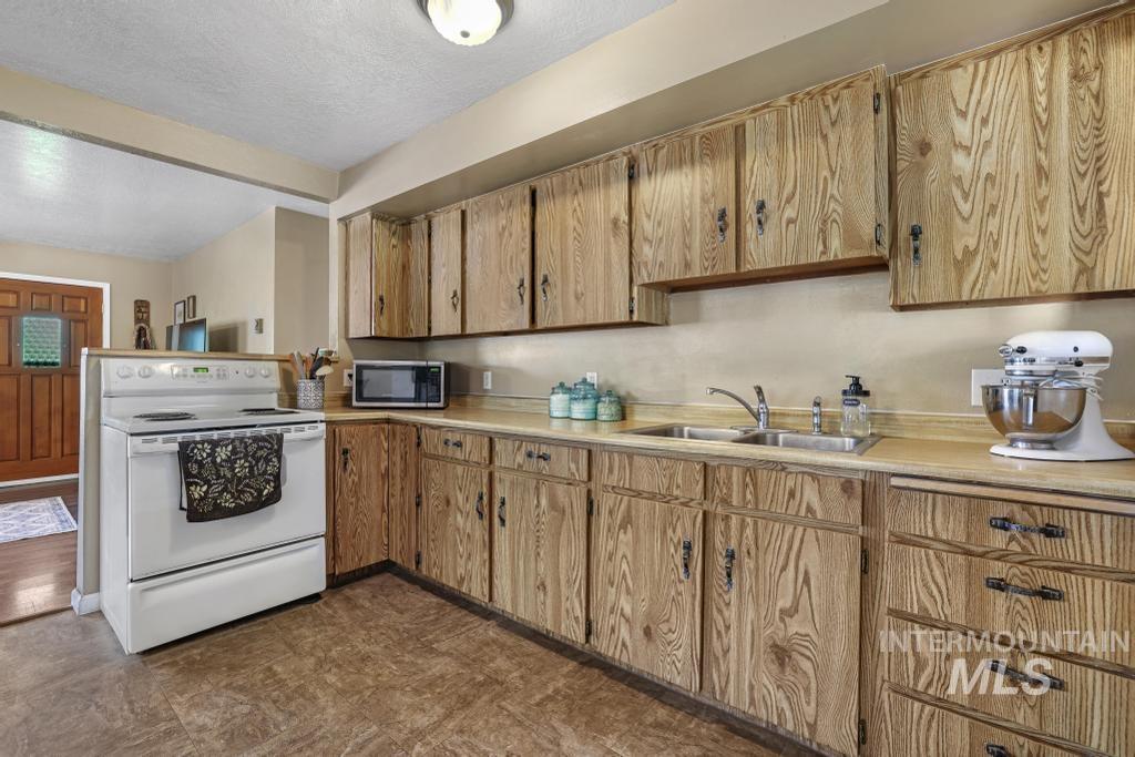 Kitchen featuring white electric stove, light countertops, stainless steel microwave, and a textured ceiling