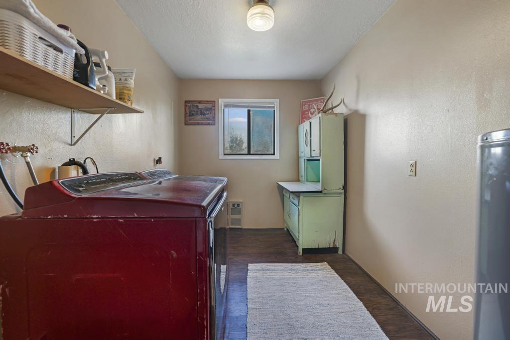 Washroom featuring a textured wall, water heater, dark wood-type flooring, hookup for a washing machine, and a textured ceiling
