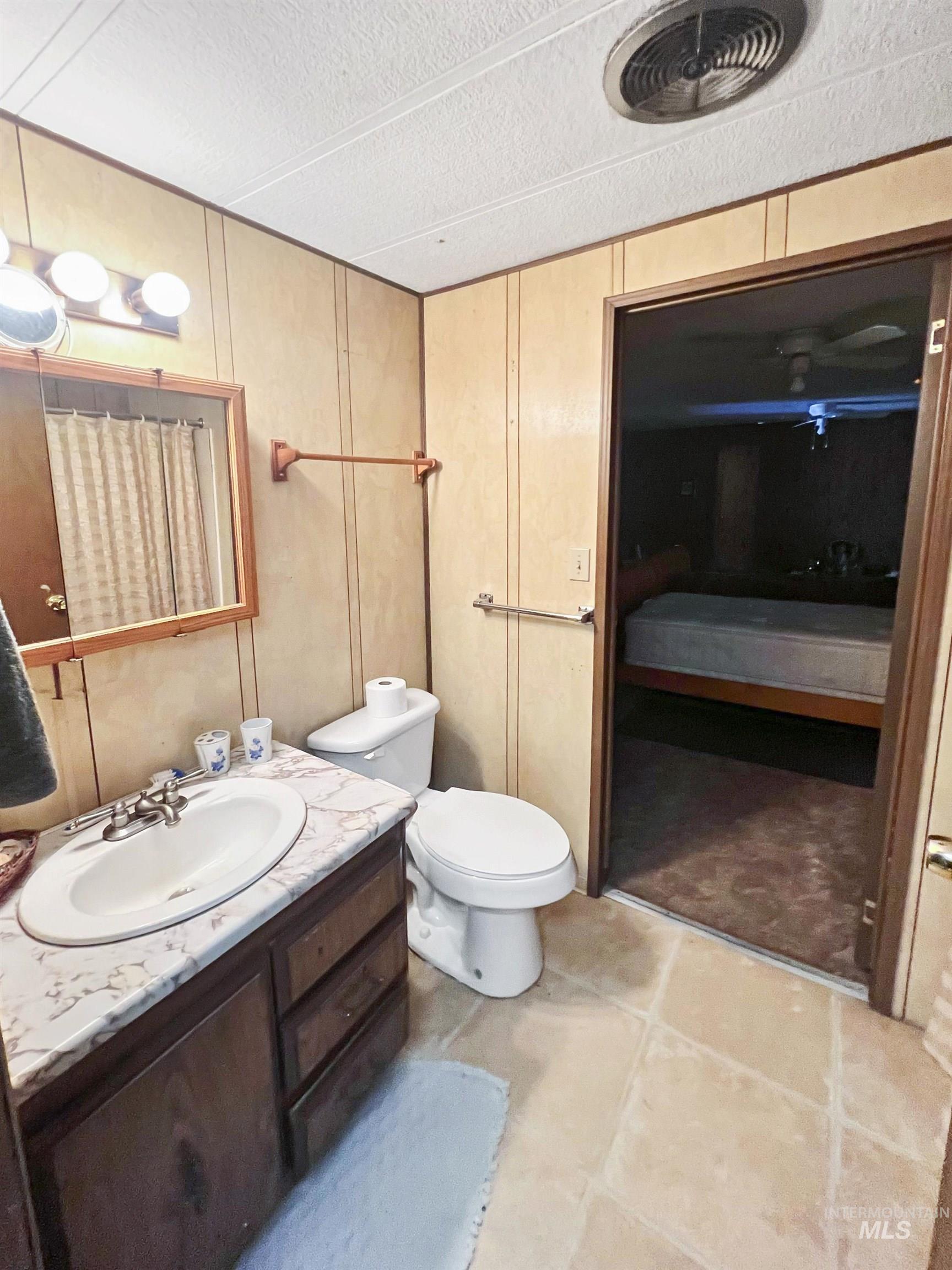Full bathroom with vanity, connected bathroom, a textured ceiling, and light tile patterned floors