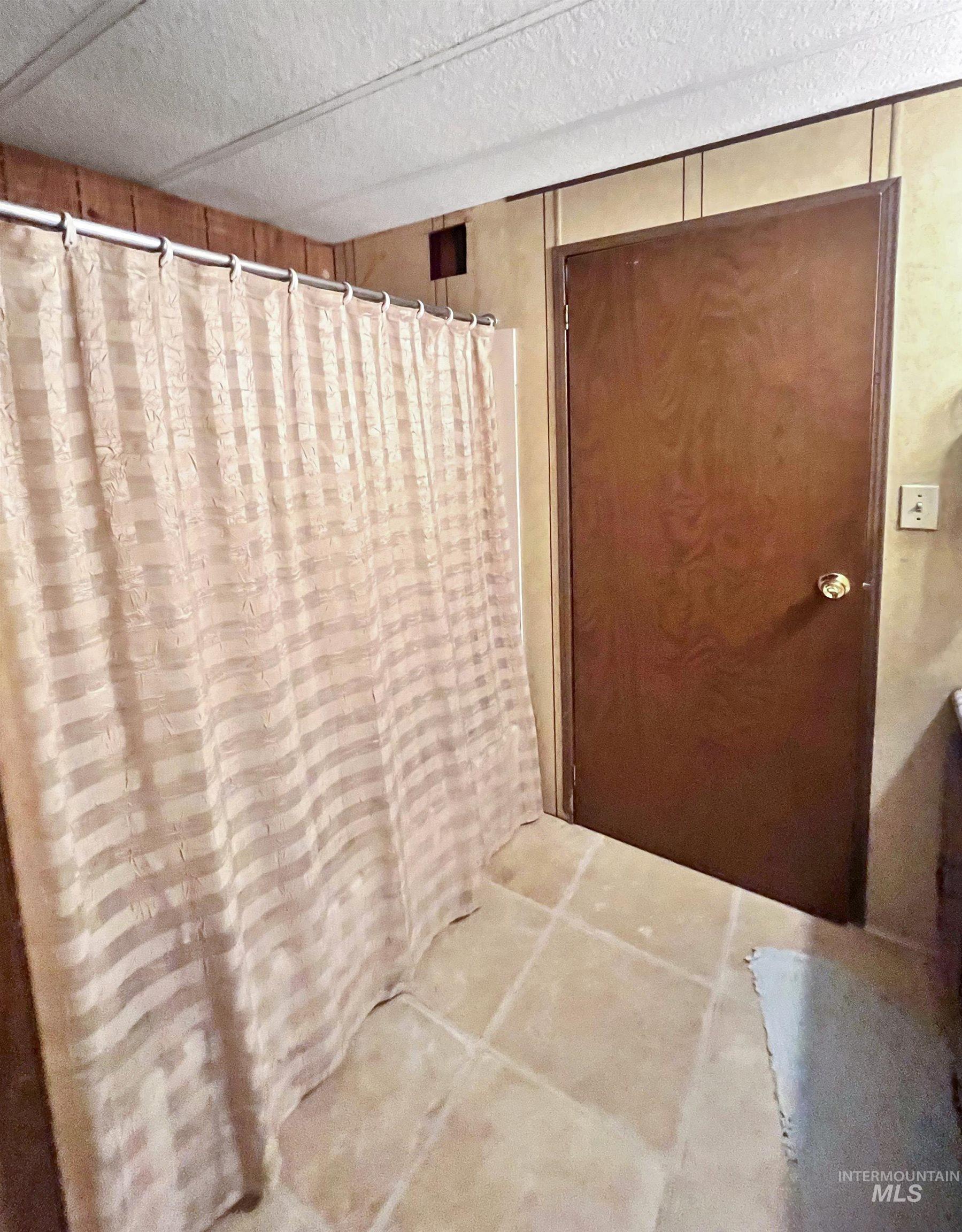 Bathroom with a textured ceiling and a shower with shower curtain