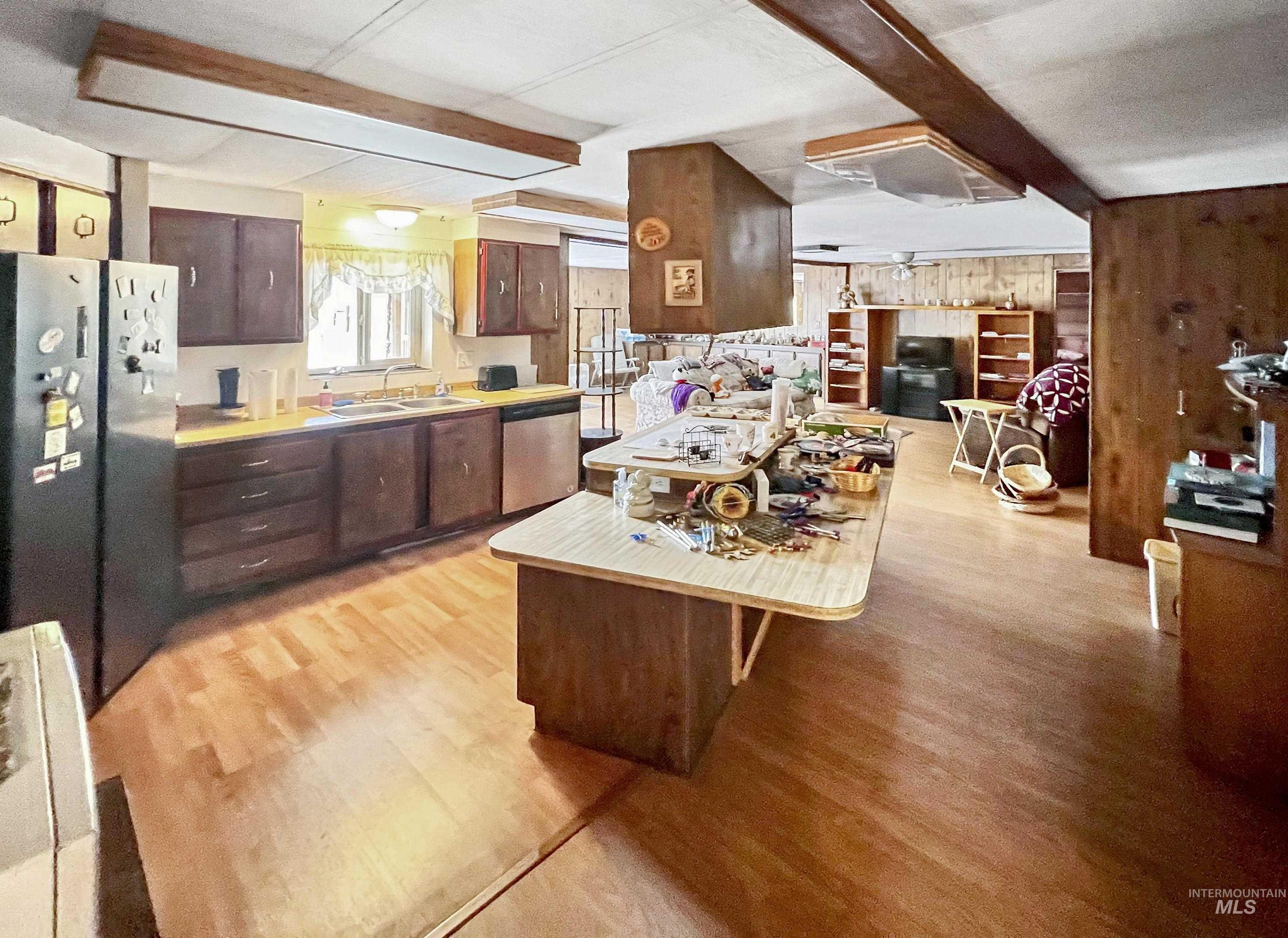 Kitchen featuring light countertops, appliances with stainless steel finishes, dark brown cabinetry, a kitchen breakfast bar, and light wood-type flooring