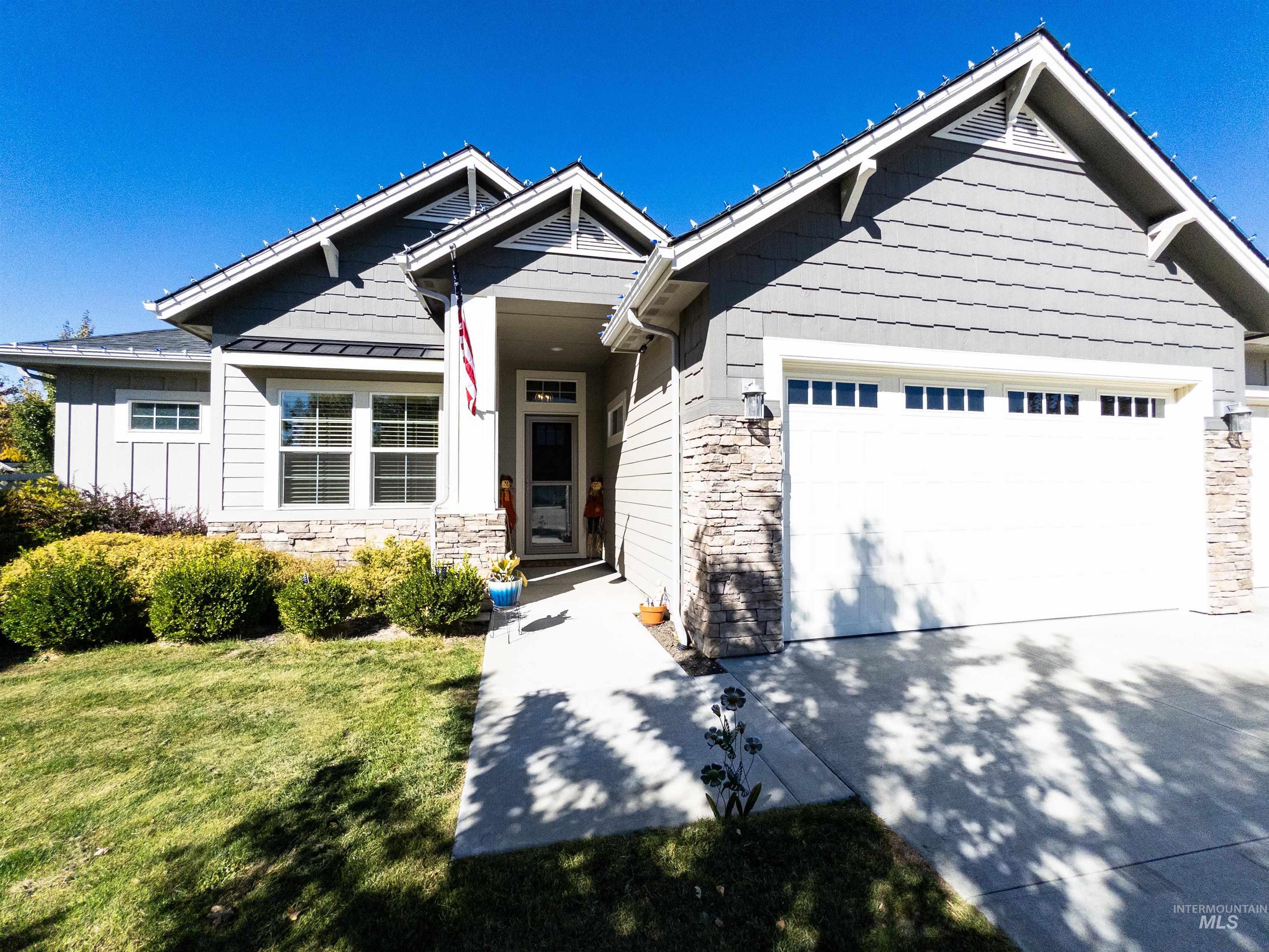 Craftsman-style house with stone siding, driveway, a front lawn, and a garage