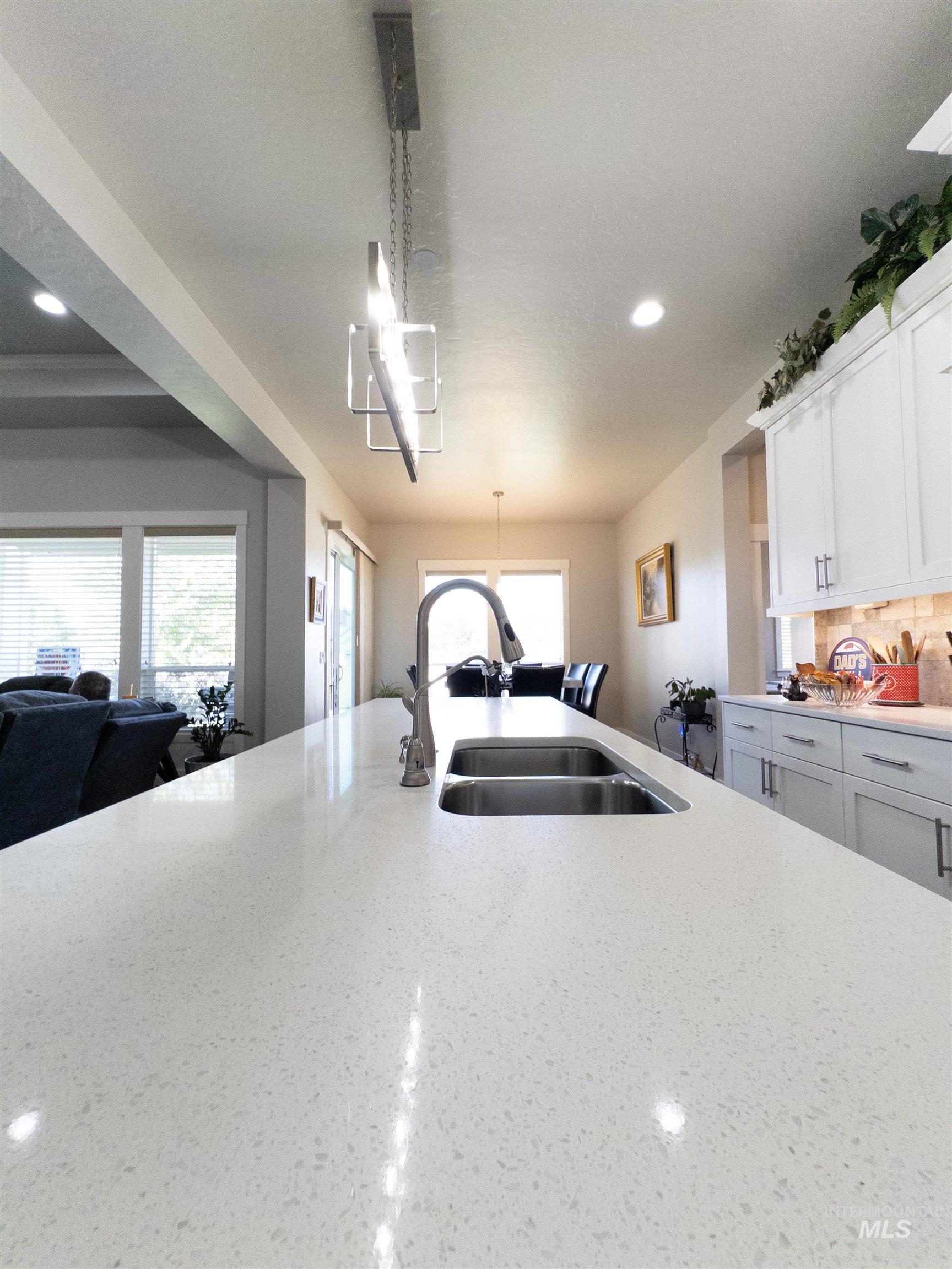 Kitchen featuring recessed lighting, open floor plan, light stone counters, white cabinetry, and decorative light fixtures