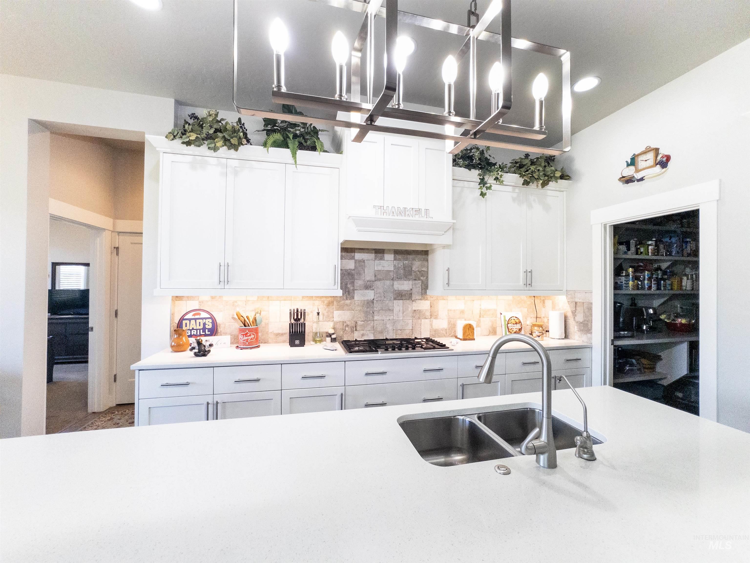 Kitchen with white cabinets, backsplash, recessed lighting, light stone countertops, and stainless steel gas stovetop