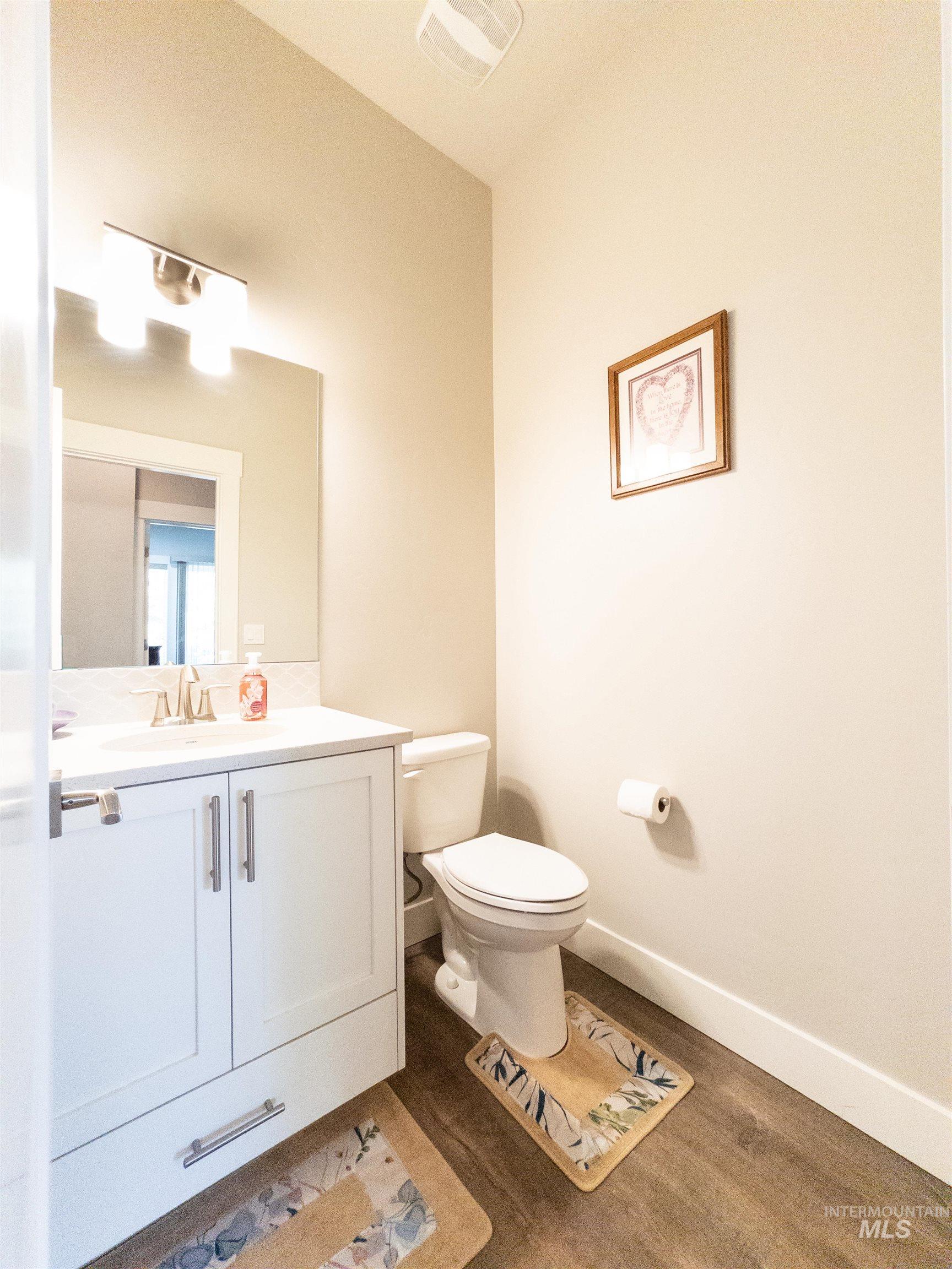Half bathroom with dark wood-type flooring and vanity