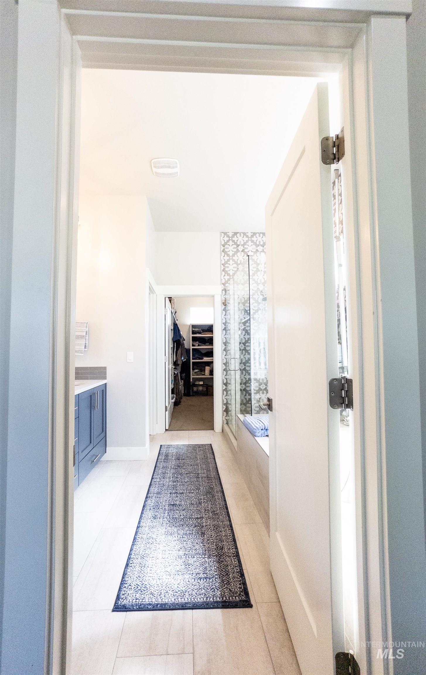 Bathroom with vanity, a spacious closet, a shower stall, light tile patterned flooring, and a bath