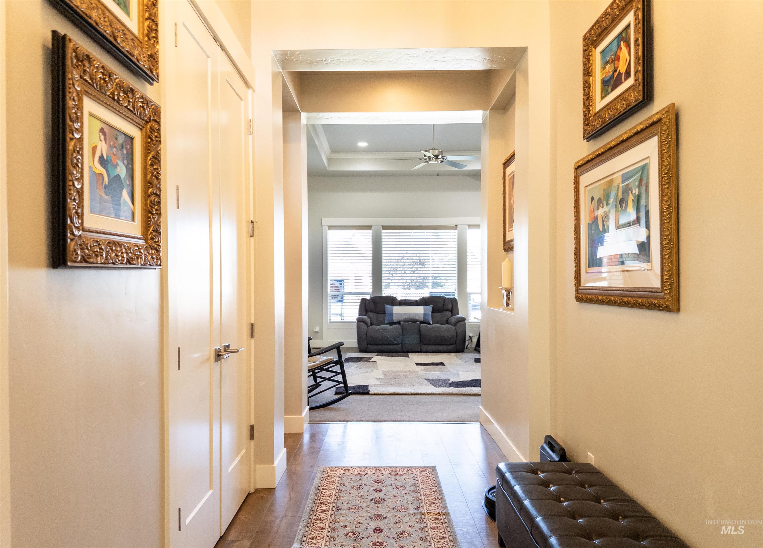 Hallway with dark wood-style flooring and a tray ceiling