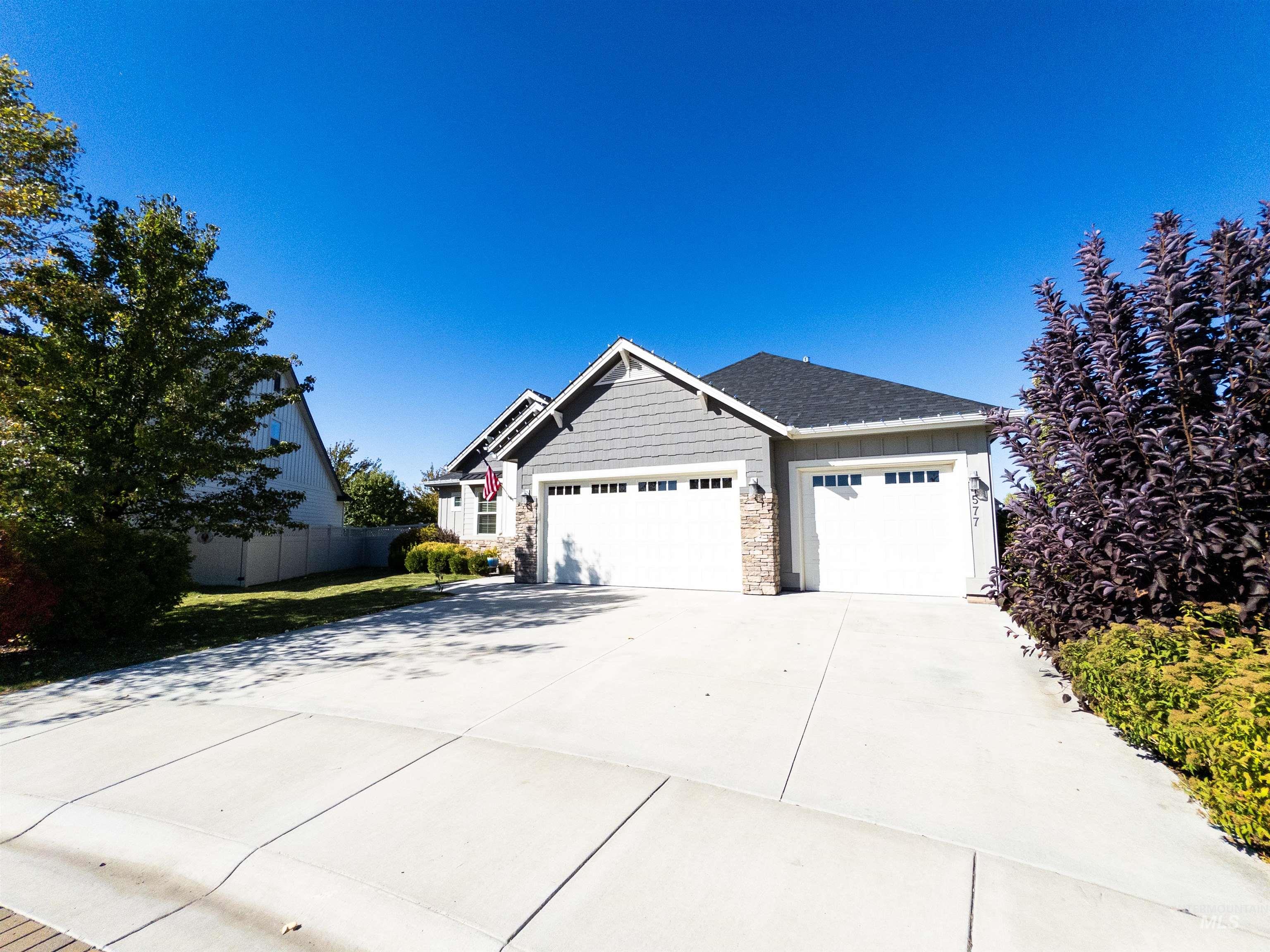 Craftsman-style house with stone siding, a garage, and concrete driveway