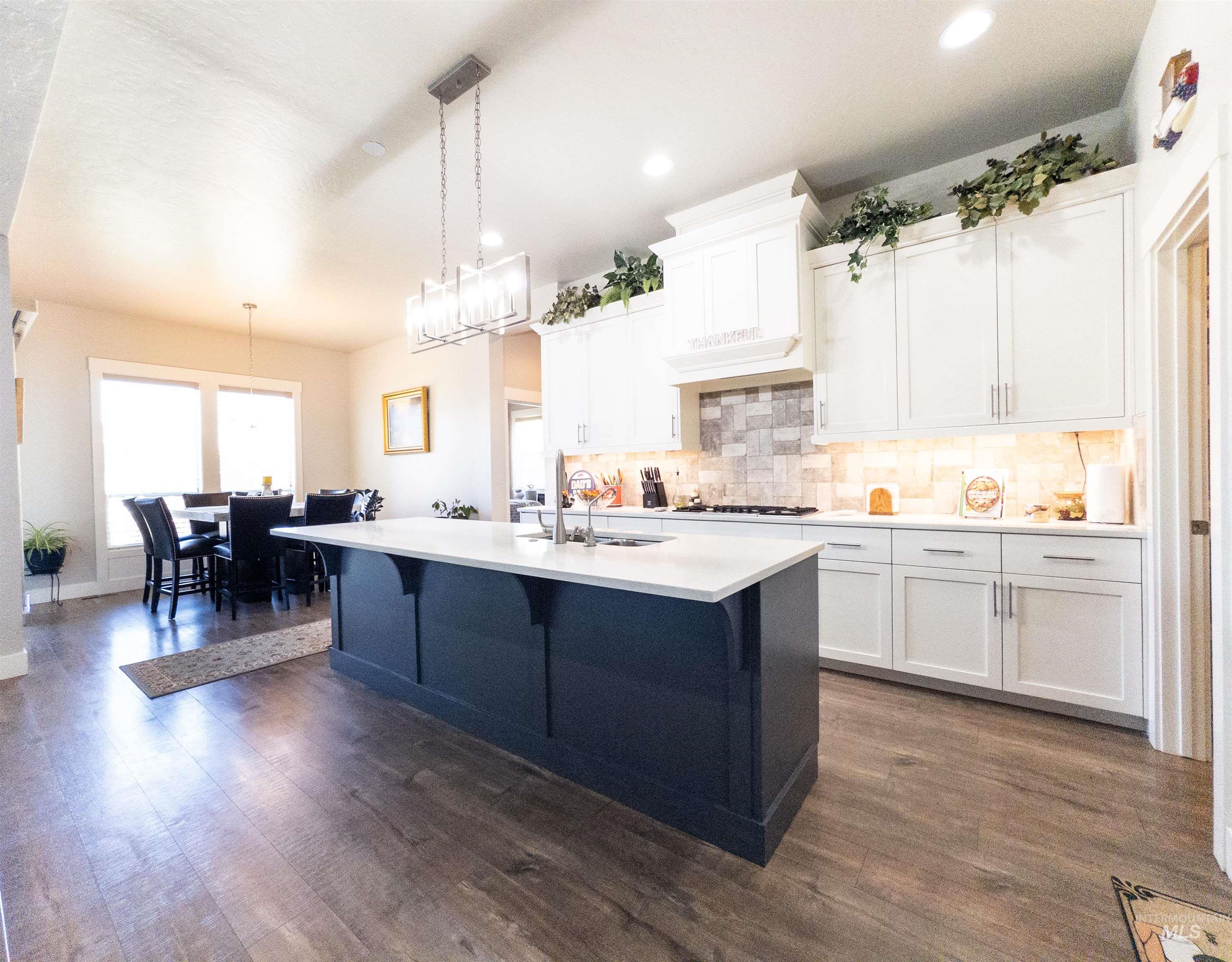 Kitchen with white cabinets, decorative light fixtures, backsplash, dark wood-style flooring, and recessed lighting