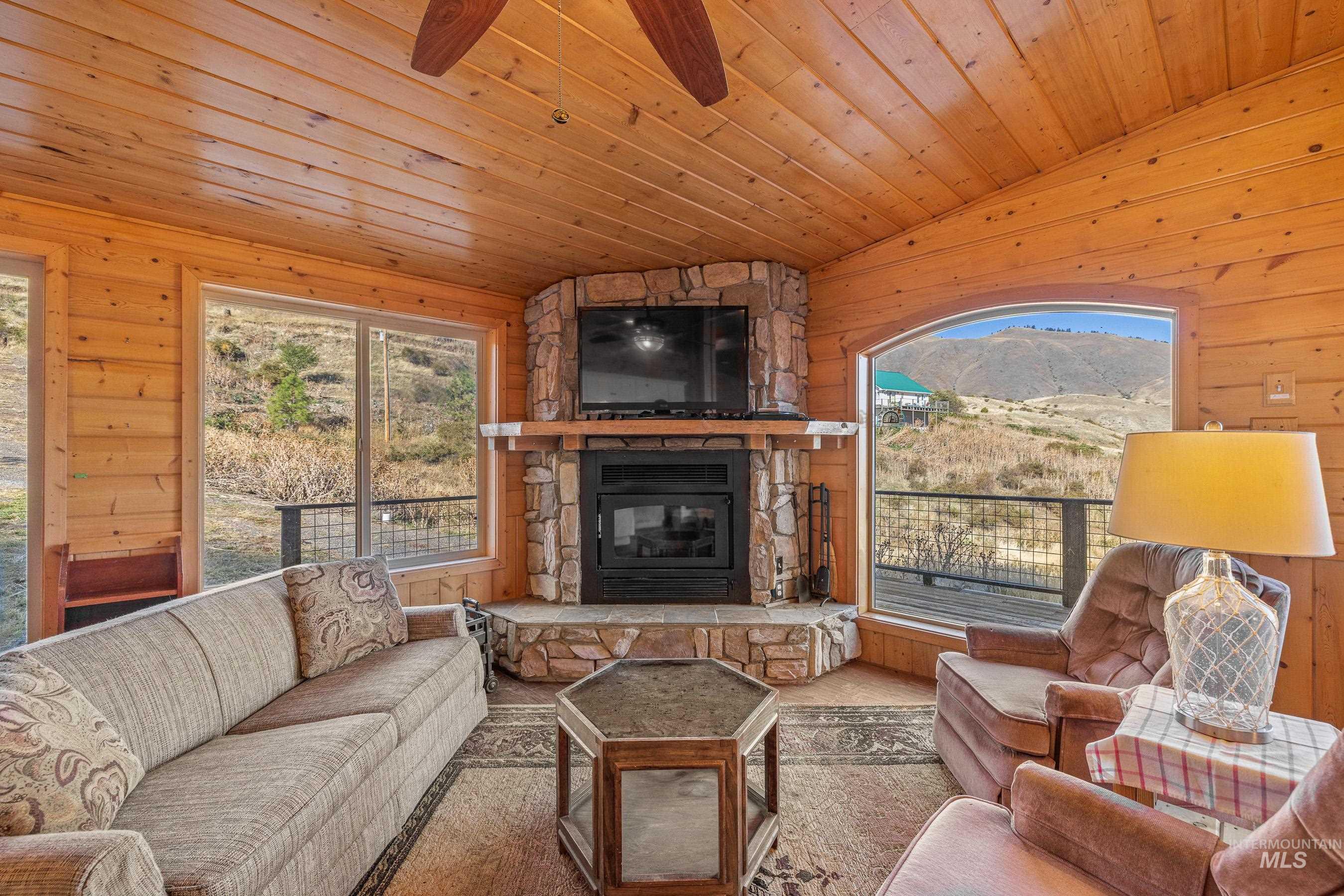 Living room featuring wood walls, lofted ceiling, plenty of natural light, a fireplace, and wood ceiling