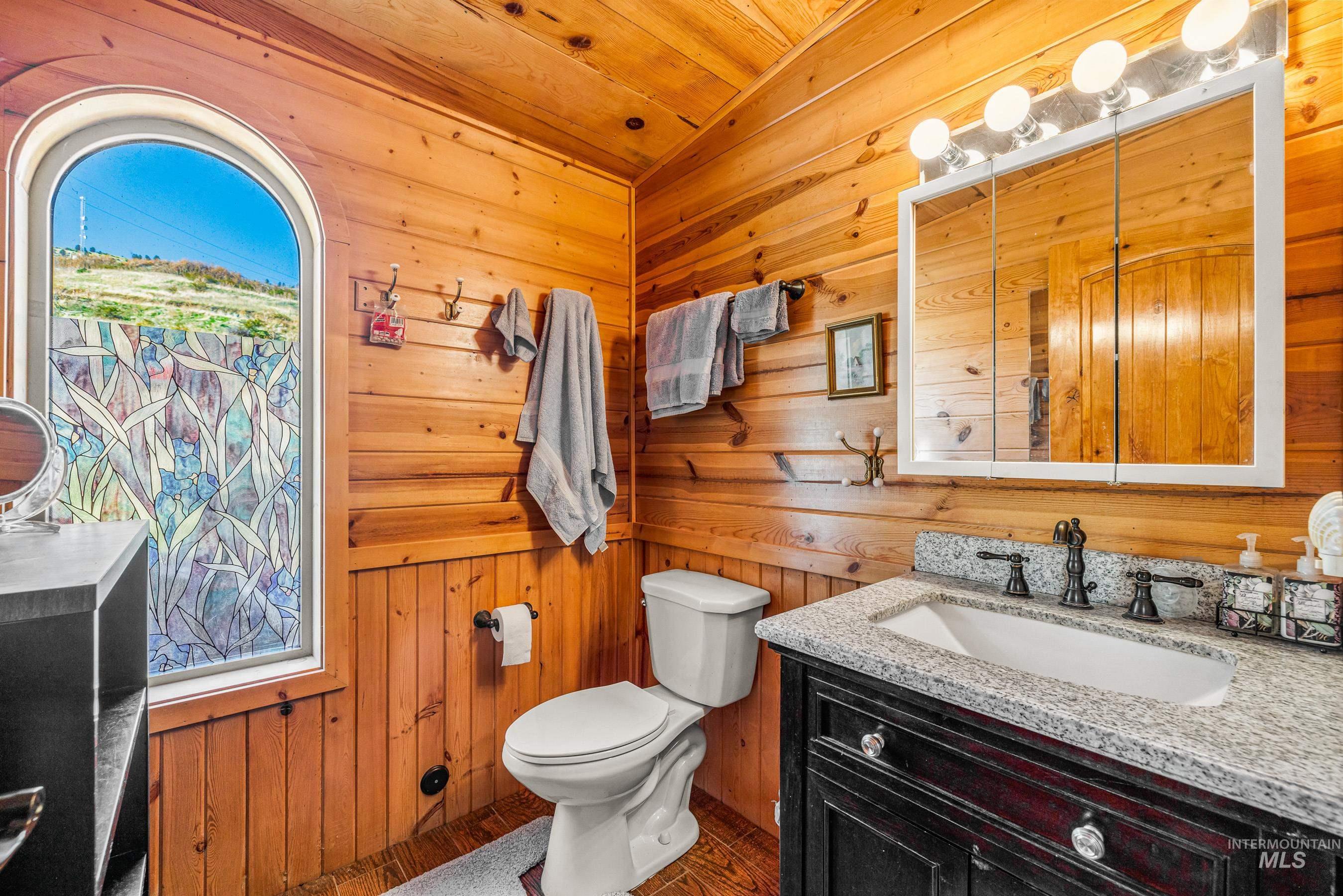Half bathroom with wood walls, vanity, and wooden ceiling