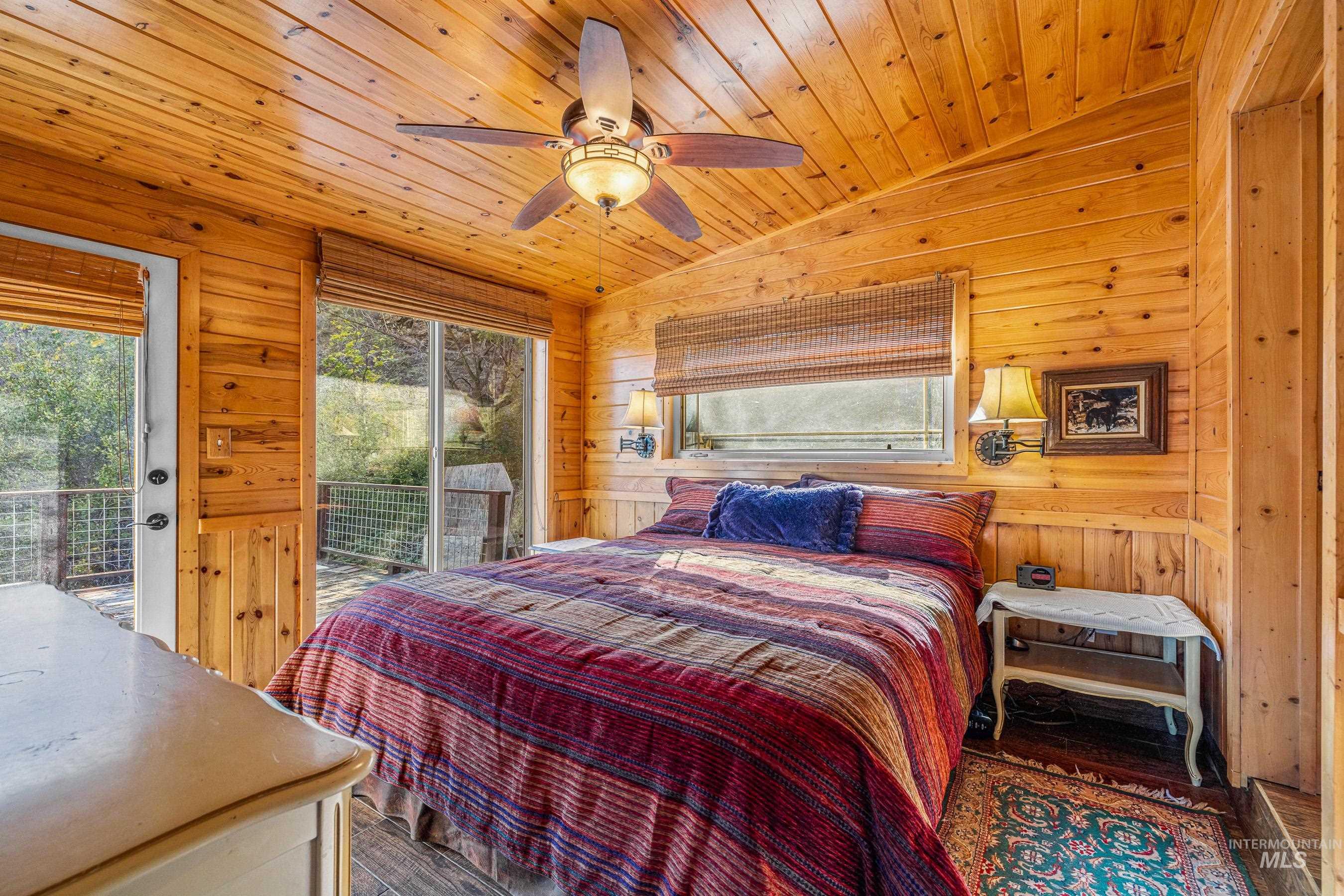 Bedroom with lofted ceiling, access to exterior, a ceiling fan, wood walls, and wood ceiling