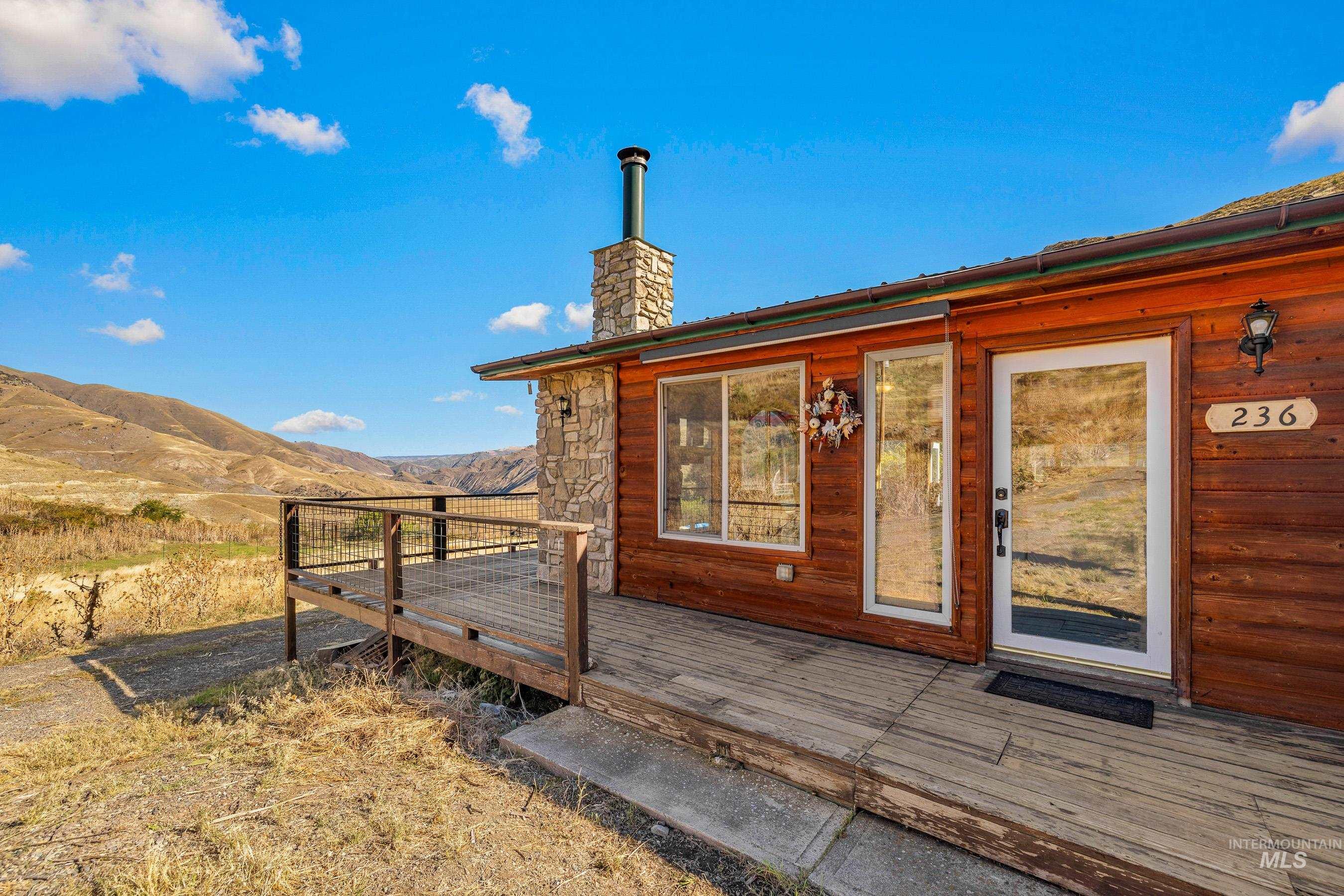 View of exterior entry featuring a deck with mountain view and a chimney