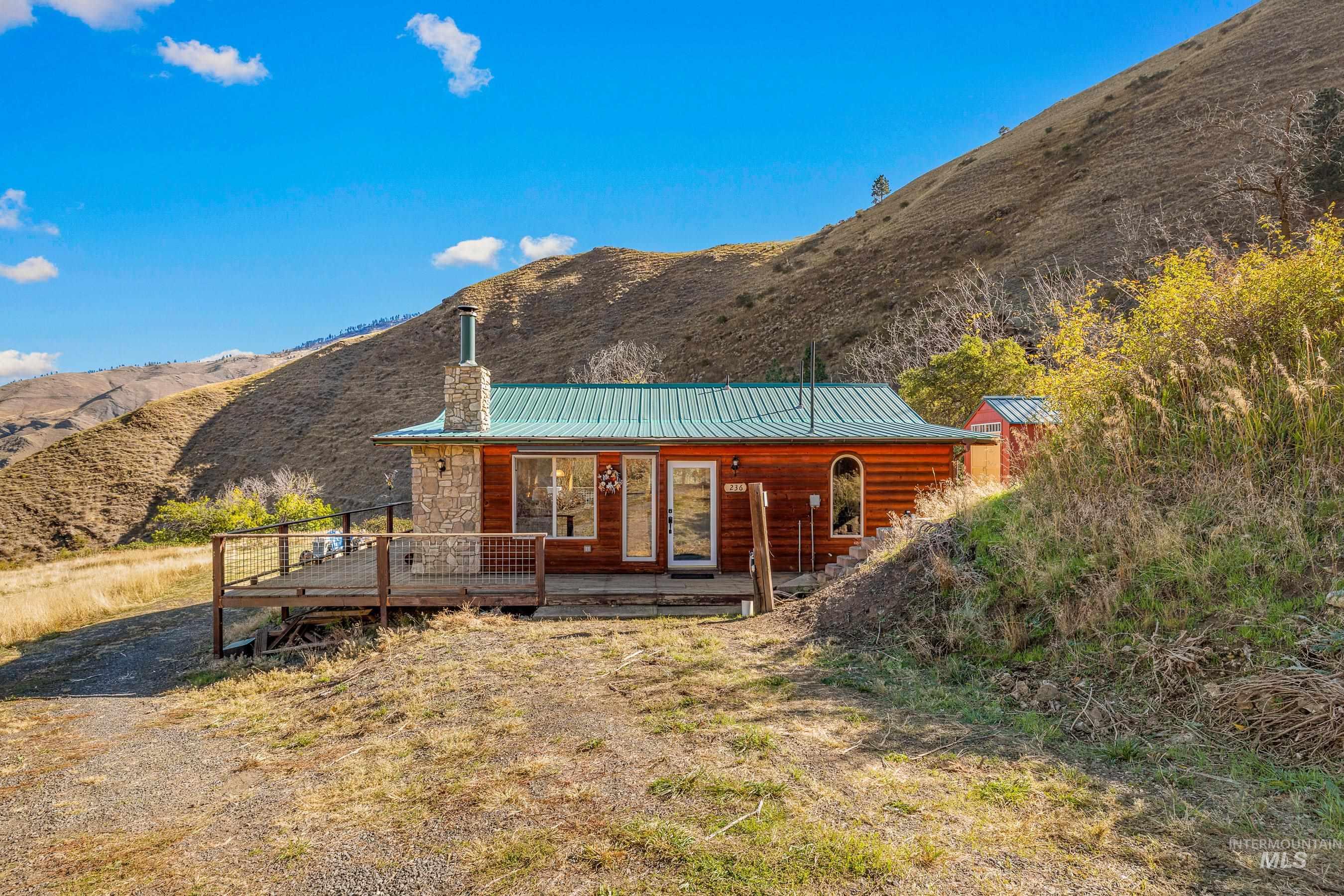 Back of property with a chimney, a metal roof, and a deck with mountain view