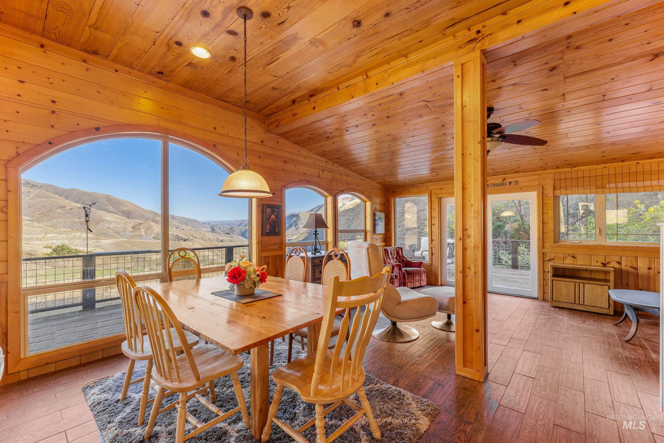 Dining area featuring a mountain view, wood walls, wood-type flooring, wood ceiling, and lofted ceiling