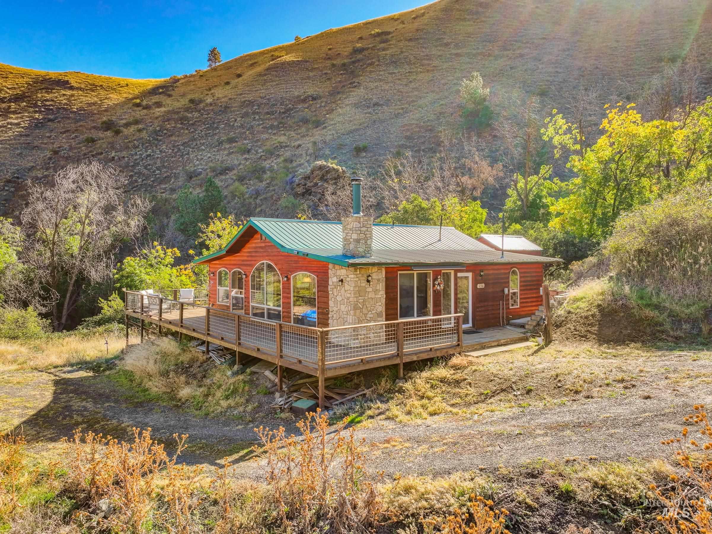 Rear view of property featuring a deck, a chimney, and a metal roof