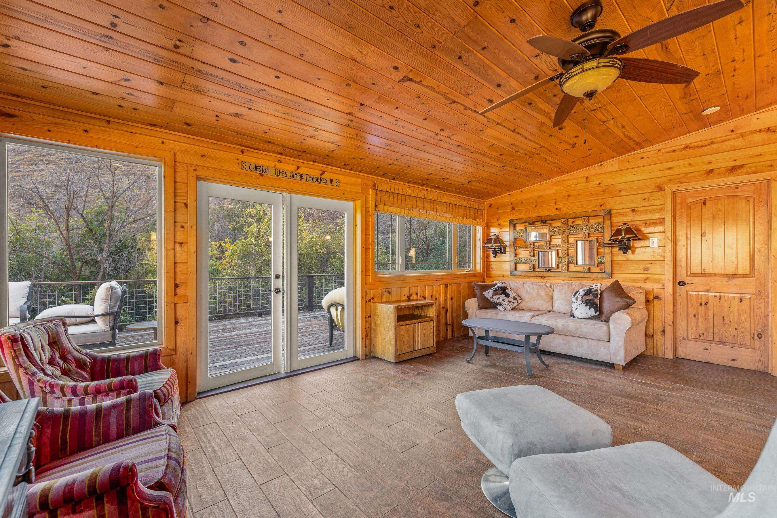 Living room with vaulted ceiling, wood finished floors, wooden ceiling, and a ceiling fan