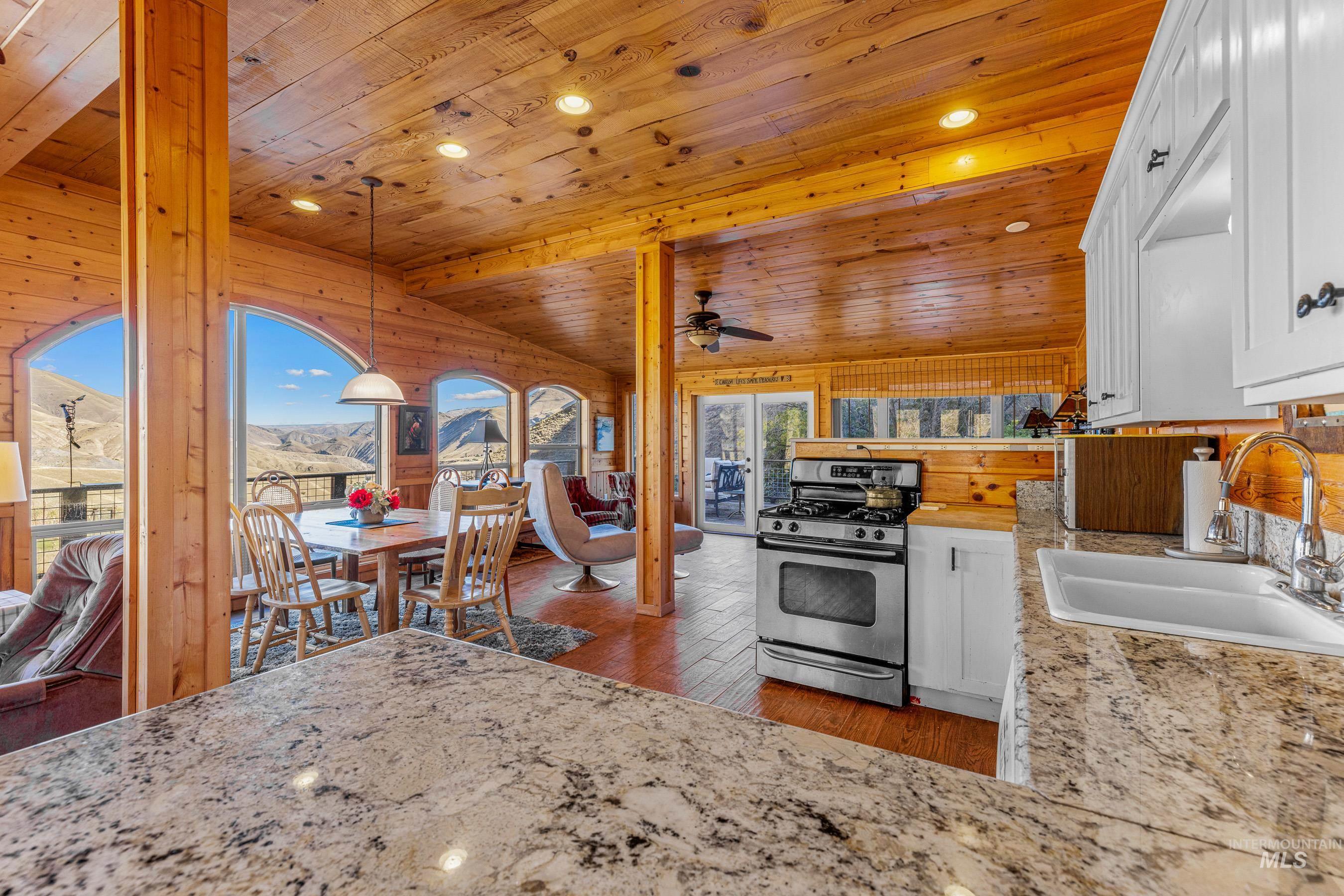 Kitchen with stainless steel gas range, dark wood finished floors, a mountain view, decorative light fixtures, and white cabinets