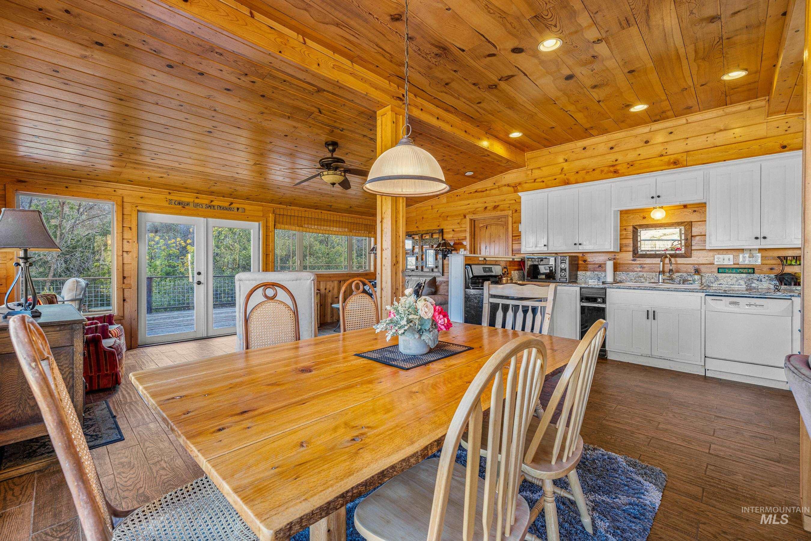 Dining room with dark wood finished floors, recessed lighting, wood walls, french doors, and ceiling fan