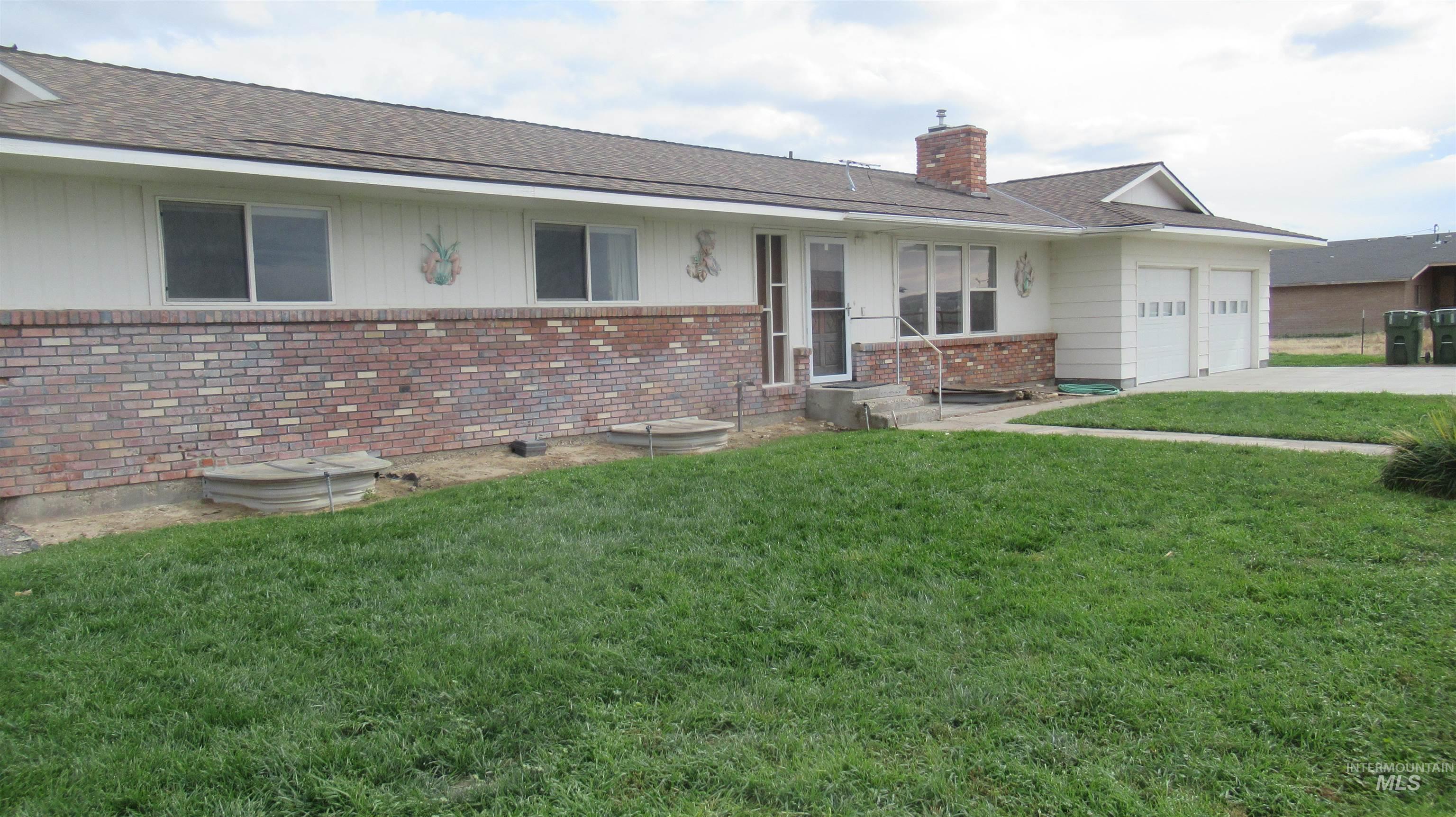 View of front of house with a front lawn, brick siding, a chimney, and roof with shingles