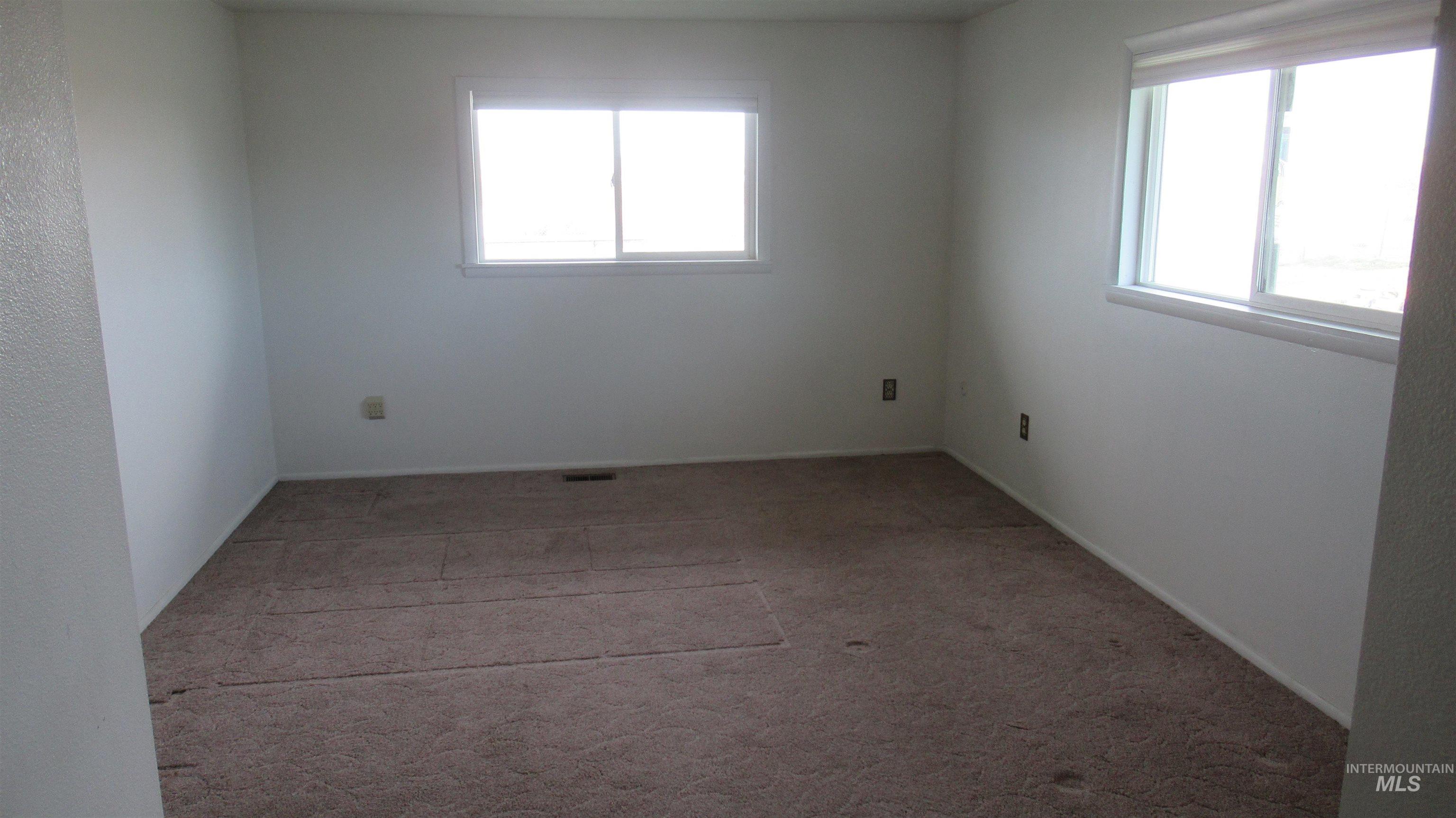 Empty room with light colored carpet and baseboards