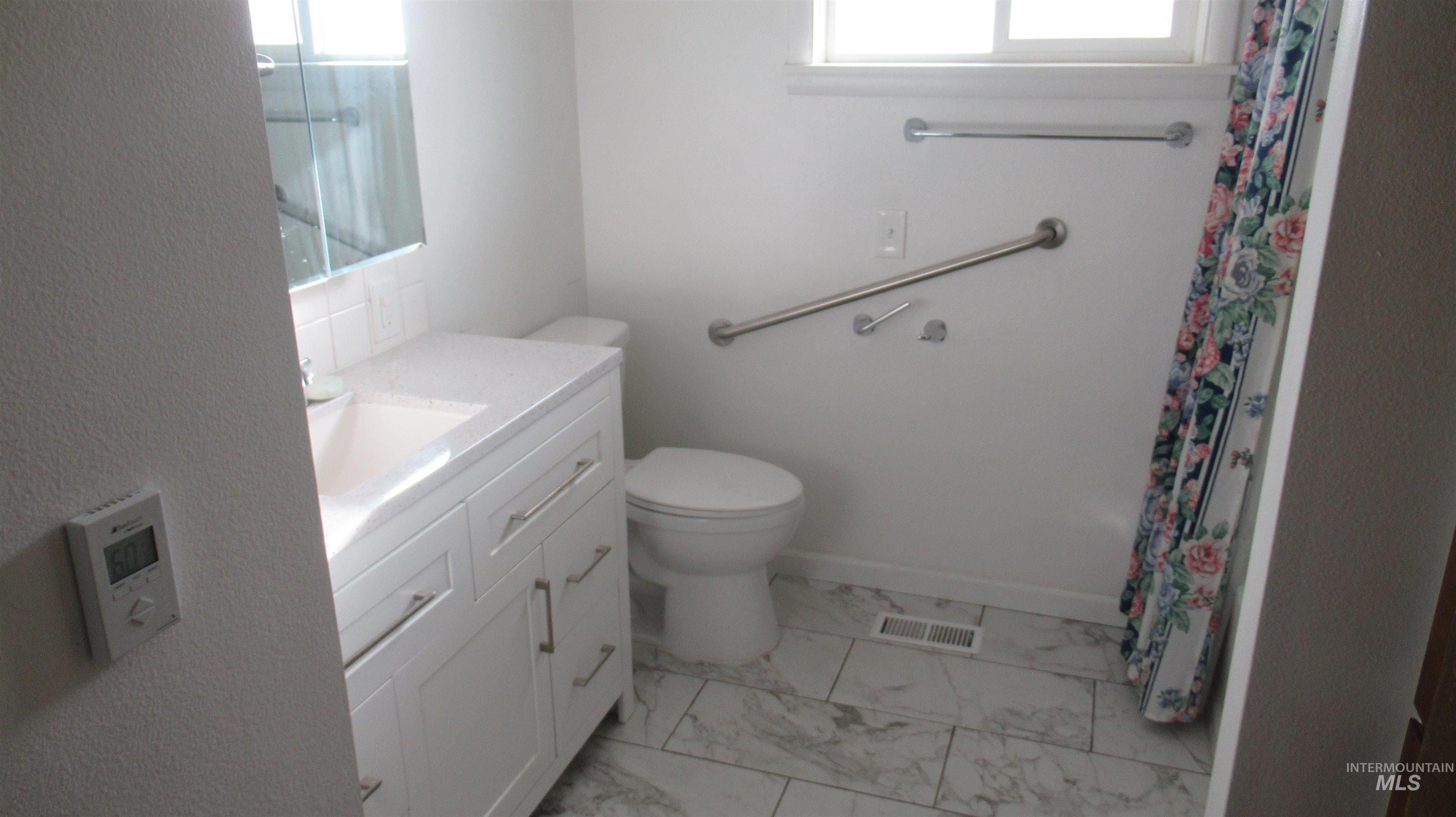 Full bath featuring vanity, light marble finish floors, and a shower with curtain