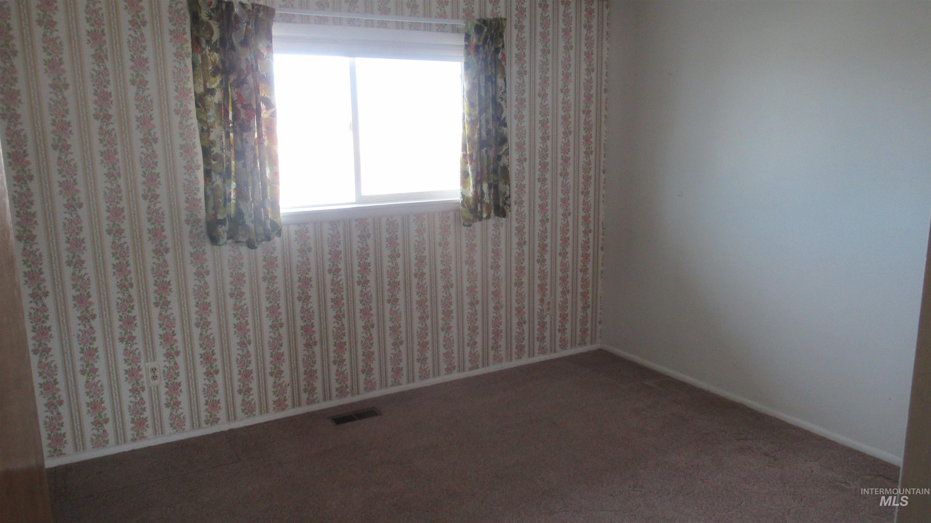 Empty room with carpet floors and wallpapered walls