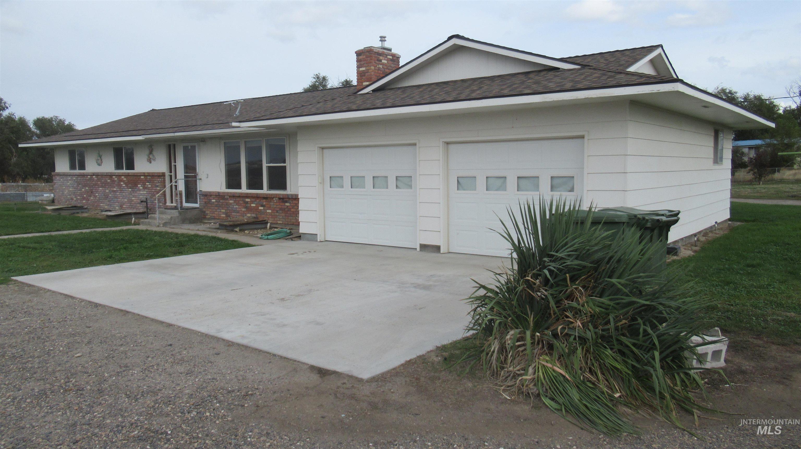 Single story home featuring brick siding, a front yard, concrete driveway, a chimney, and a garage