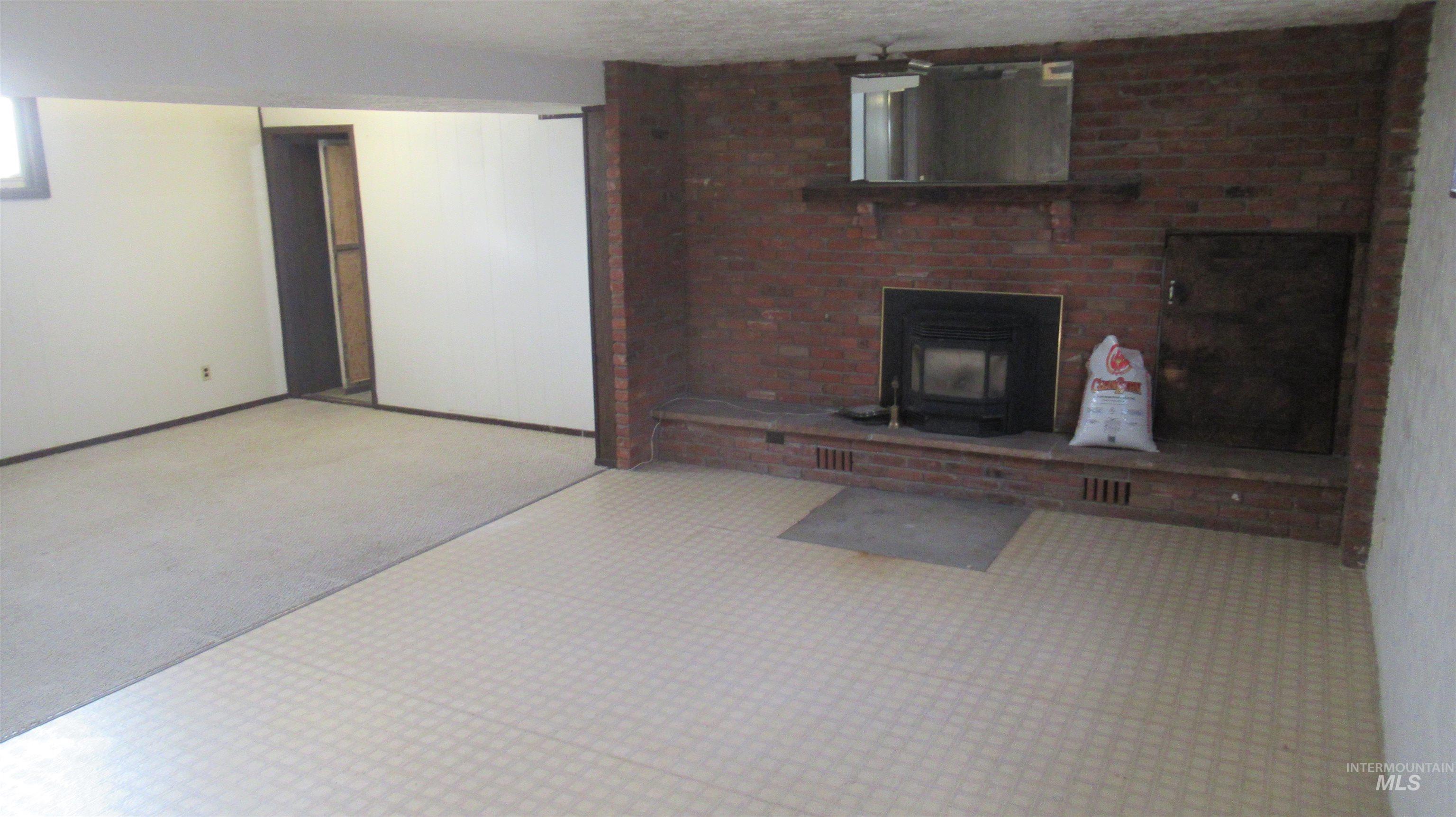 Unfurnished living room featuring a textured ceiling, a wood stove, and carpet flooring