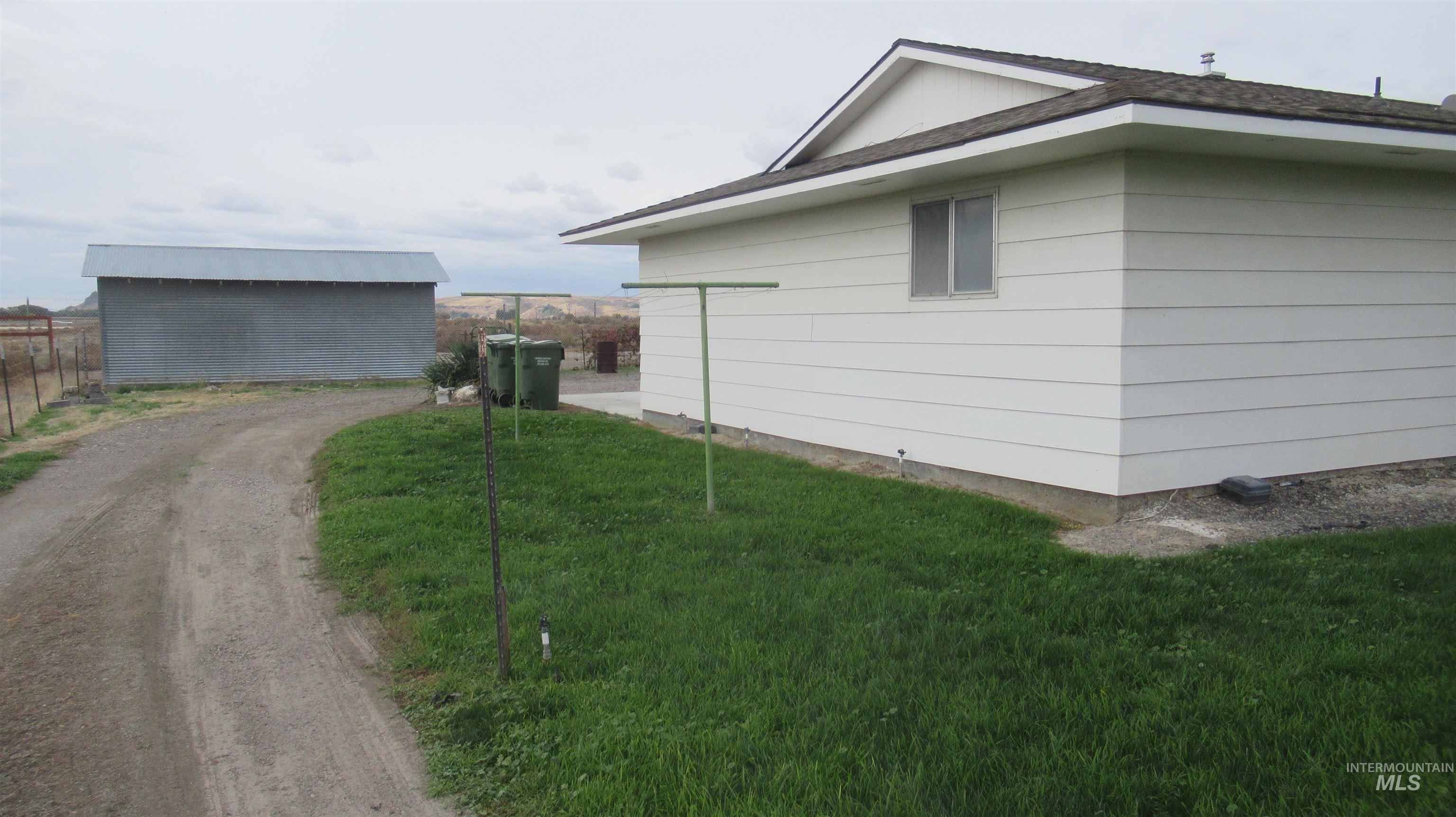 View of side of home with a lawn, an outdoor structure, and a shingled roof