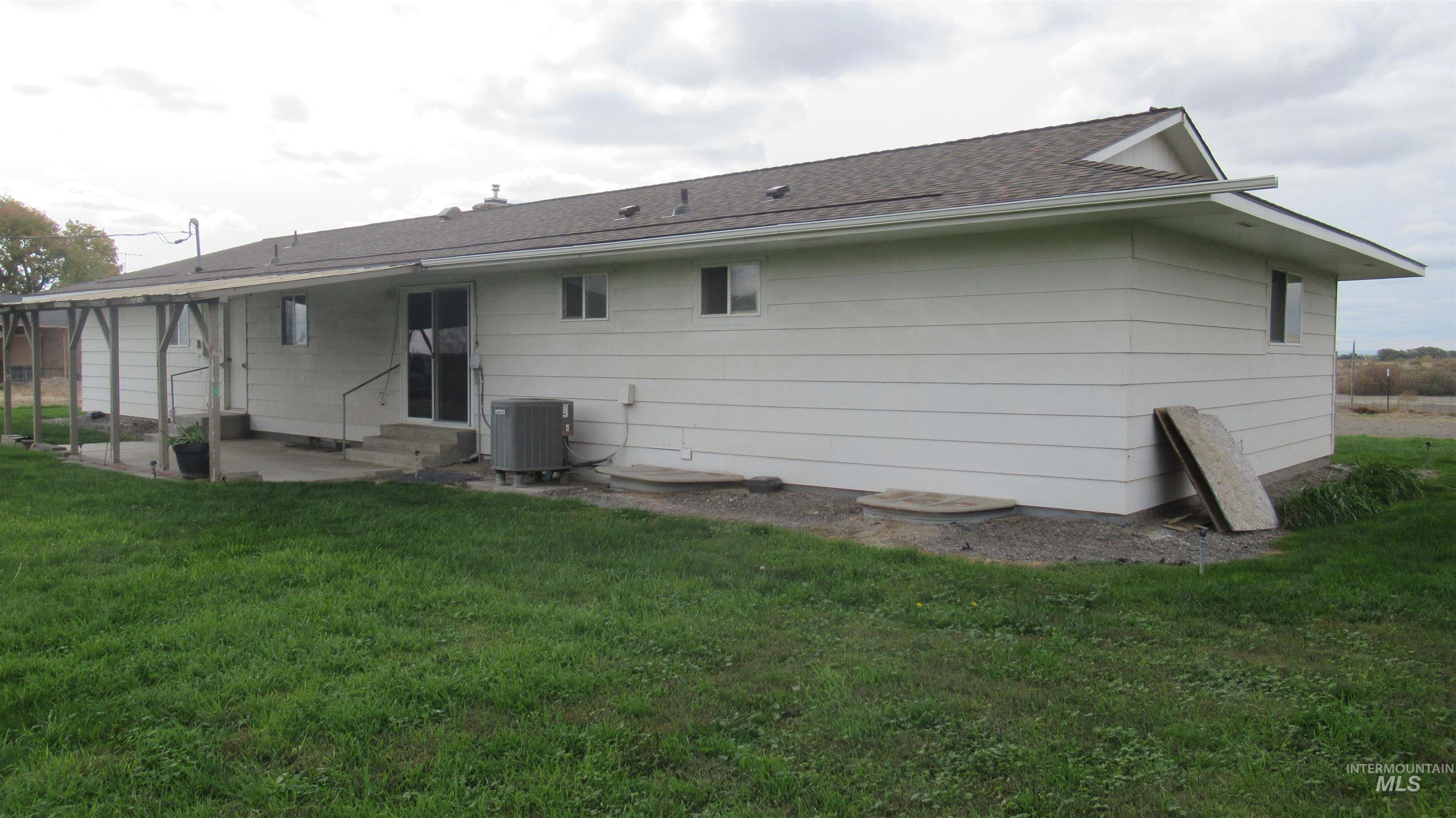 Rear view of house with entry steps, a lawn, and roof with shingles