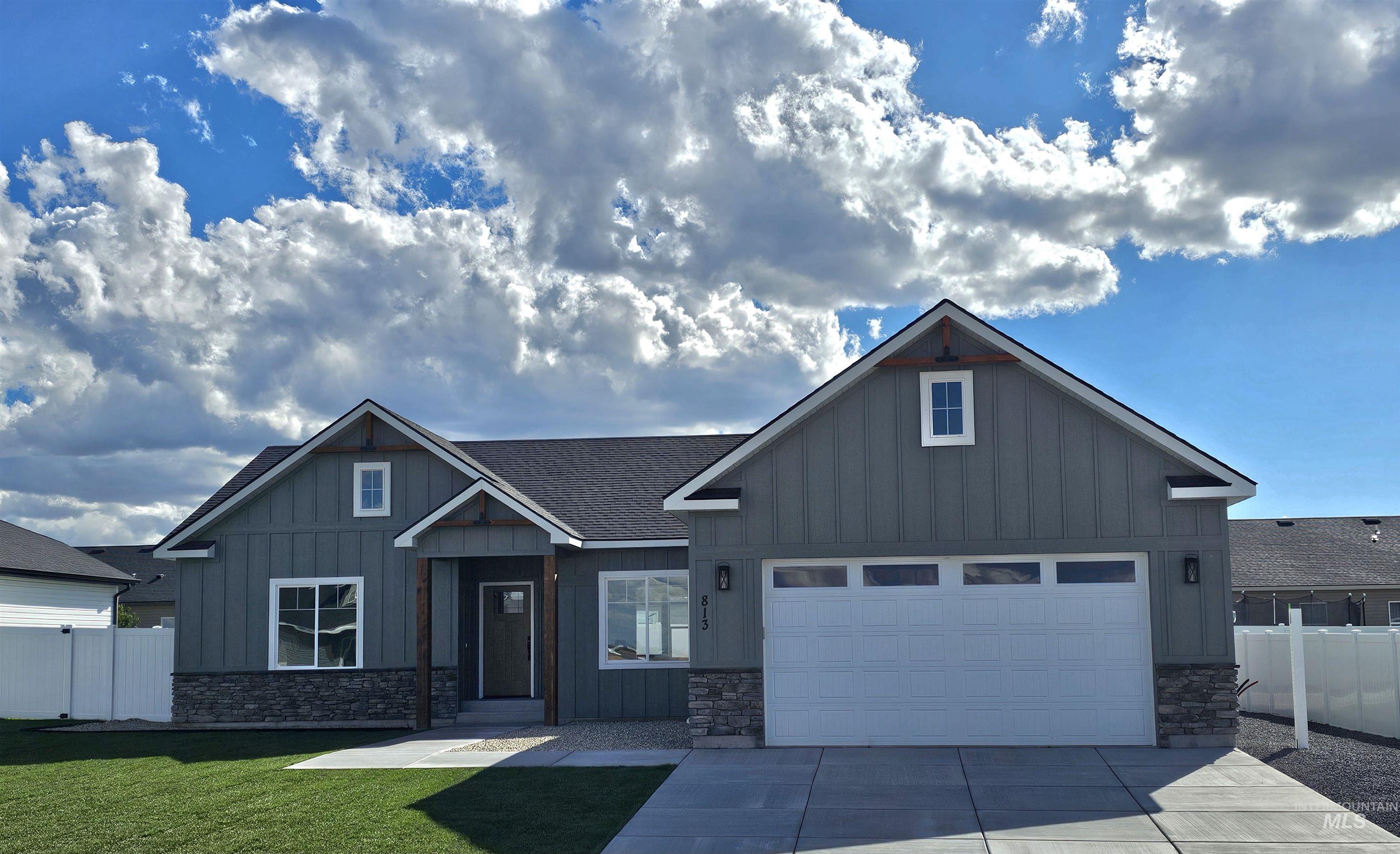 View of front of house with board and batten siding, stone siding, concrete driveway, and a garage