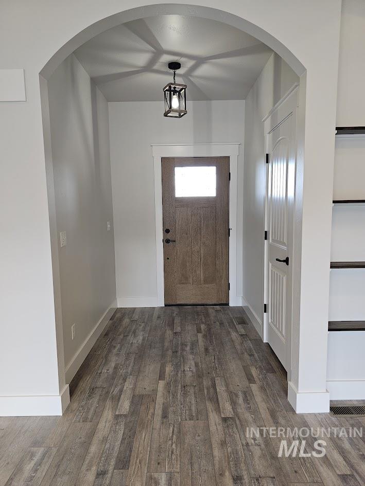 Entryway featuring arched walkways and dark wood finished floors