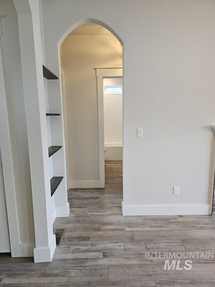 Unfurnished dining area with arched walkways and wood finished floors
