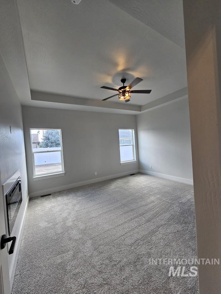 Spare room featuring a raised ceiling, light carpet, and a textured ceiling