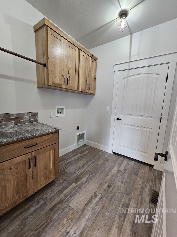 Washroom with washer hookup, dark wood-style floors, cabinet space, and electric dryer hookup
