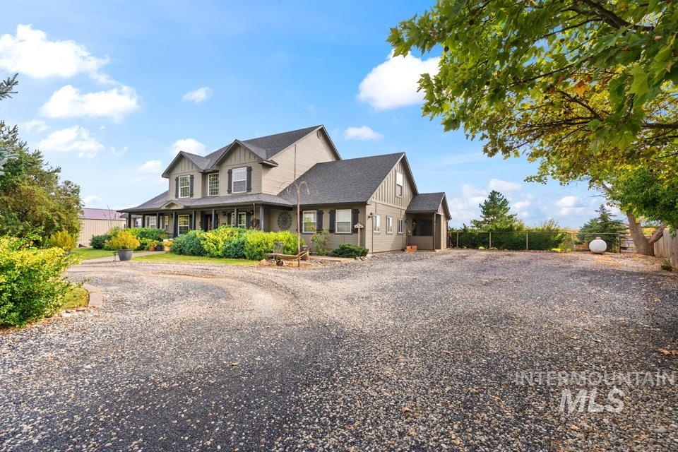 View of front of property with driveway, board and batten siding, covered porch, and a shingled roof