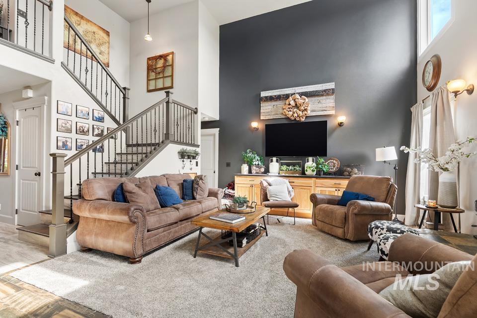 Living room with a high ceiling, stairway, healthy amount of natural light, and wood finished floors