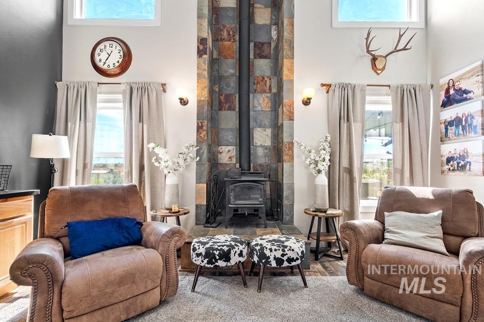 Living area with a wood stove, healthy amount of natural light, a towering ceiling, and wood finished floors