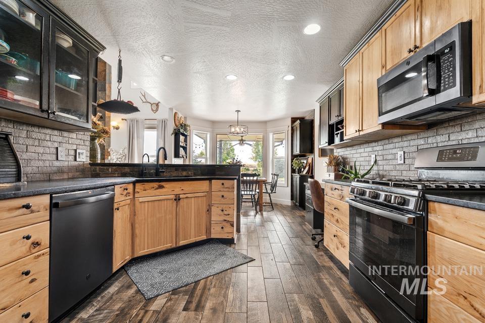 Kitchen with tasteful backsplash, stainless steel appliances, a textured ceiling, dark wood-type flooring, and recessed lighting