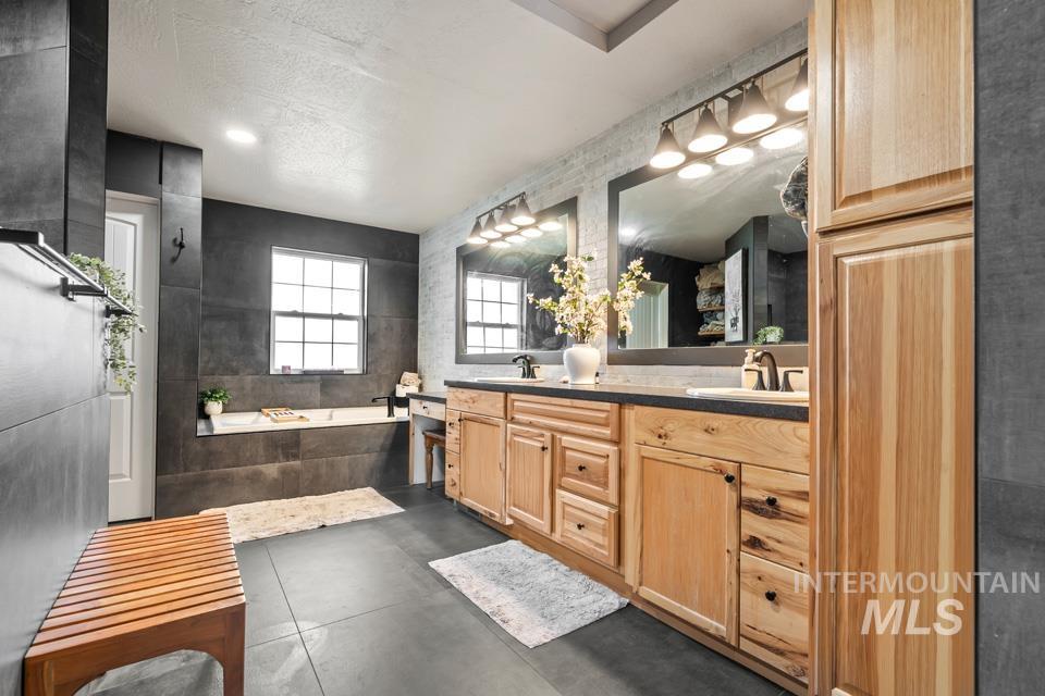 Bathroom featuring double vanity, a garden tub, tile walls, and a textured ceiling