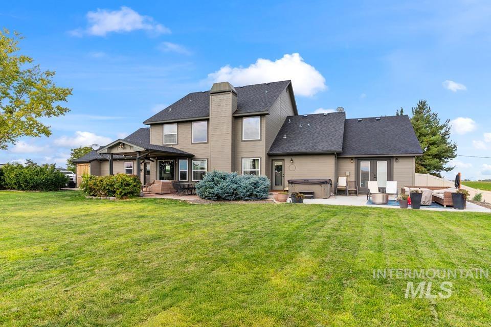 Rear view of house with a hot tub, a patio area, a yard, and outdoor lounge area