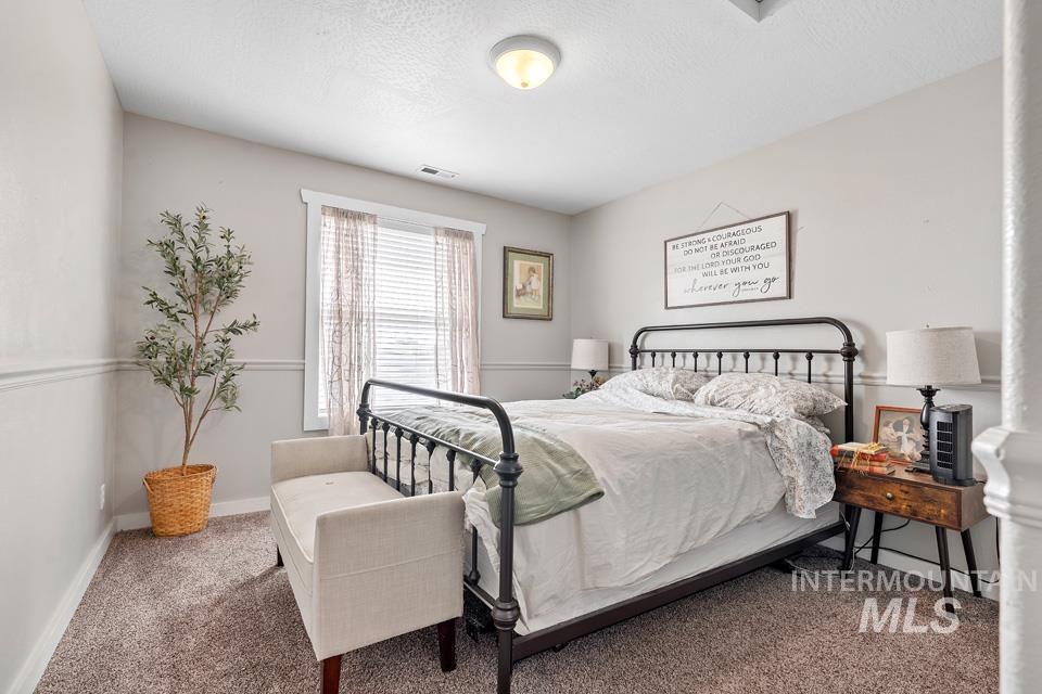 Carpeted bedroom featuring a textured ceiling and baseboards