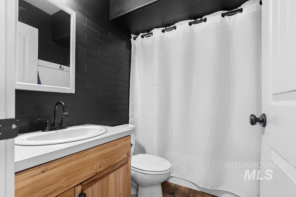 Full bath featuring vanity and dark wood-style floors