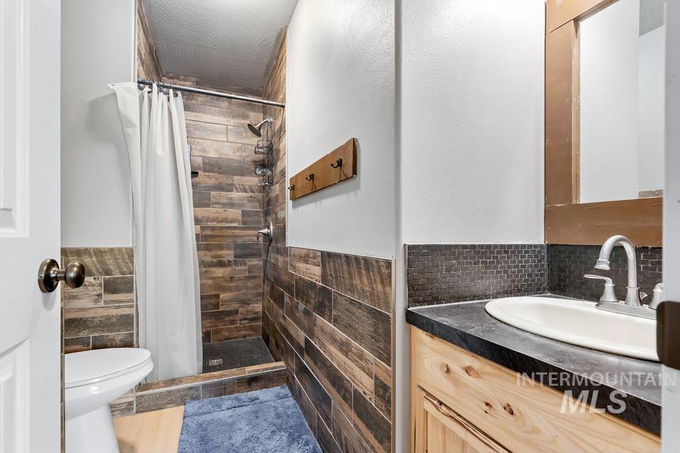 Full bathroom with vanity, tile walls, a shower stall, and a wainscoted wall