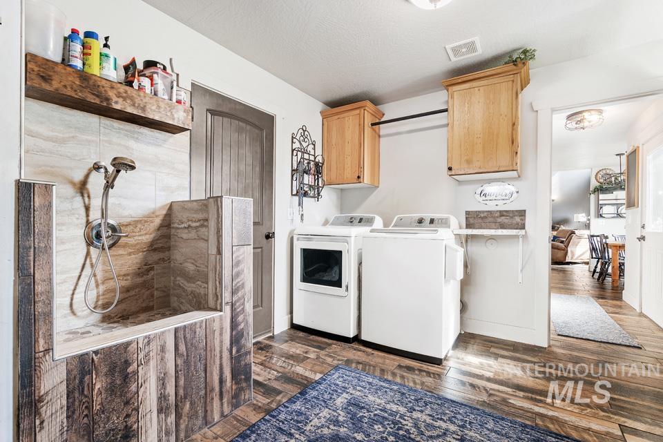 Laundry area featuring dark wood-style flooring, washer and dryer, and cabinet space