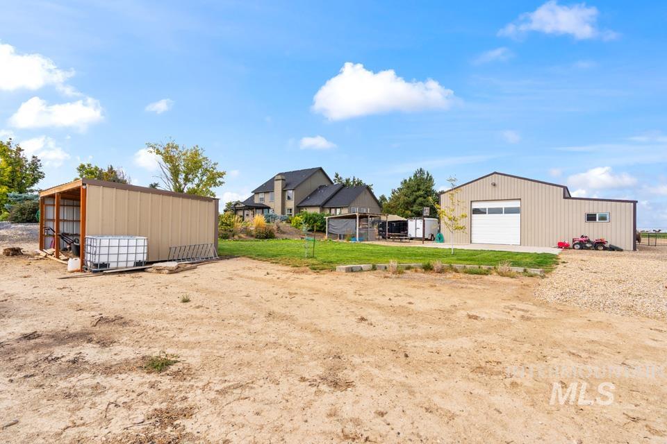 View of green lawn with an outdoor structure, a garage, and an outbuilding