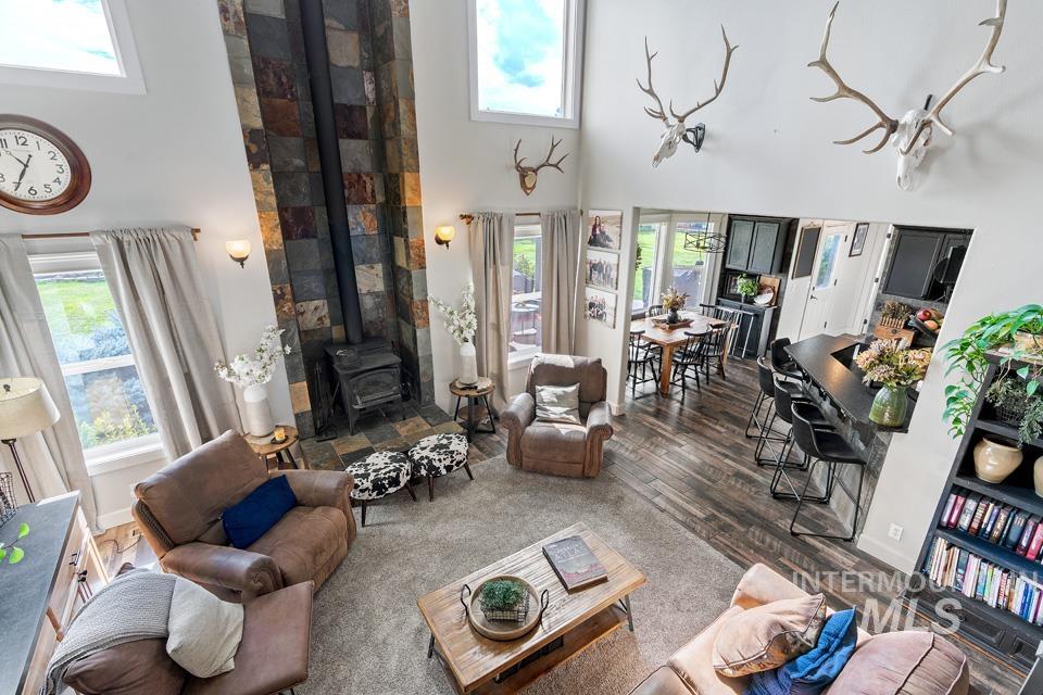 Living area featuring a wood stove, a towering ceiling, plenty of natural light, and wood finished floors