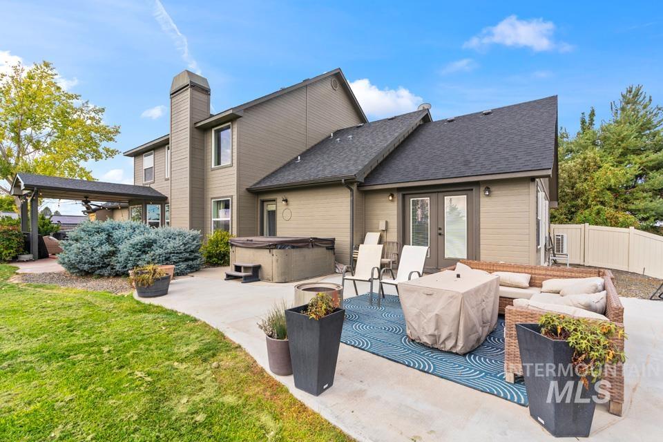 Rear view of property with a hot tub, roof with shingles, a patio, french doors, and outdoor lounge area