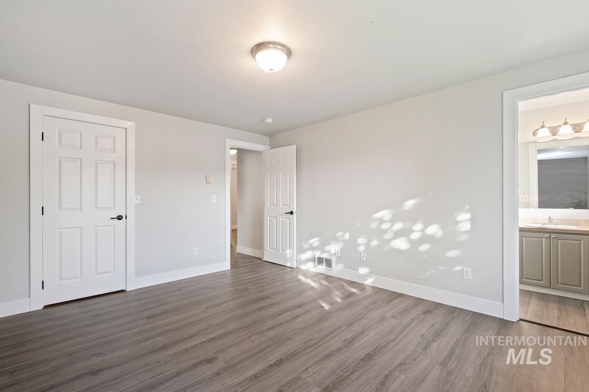 Unfurnished bedroom featuring dark wood-style flooring and ensuite bathroom